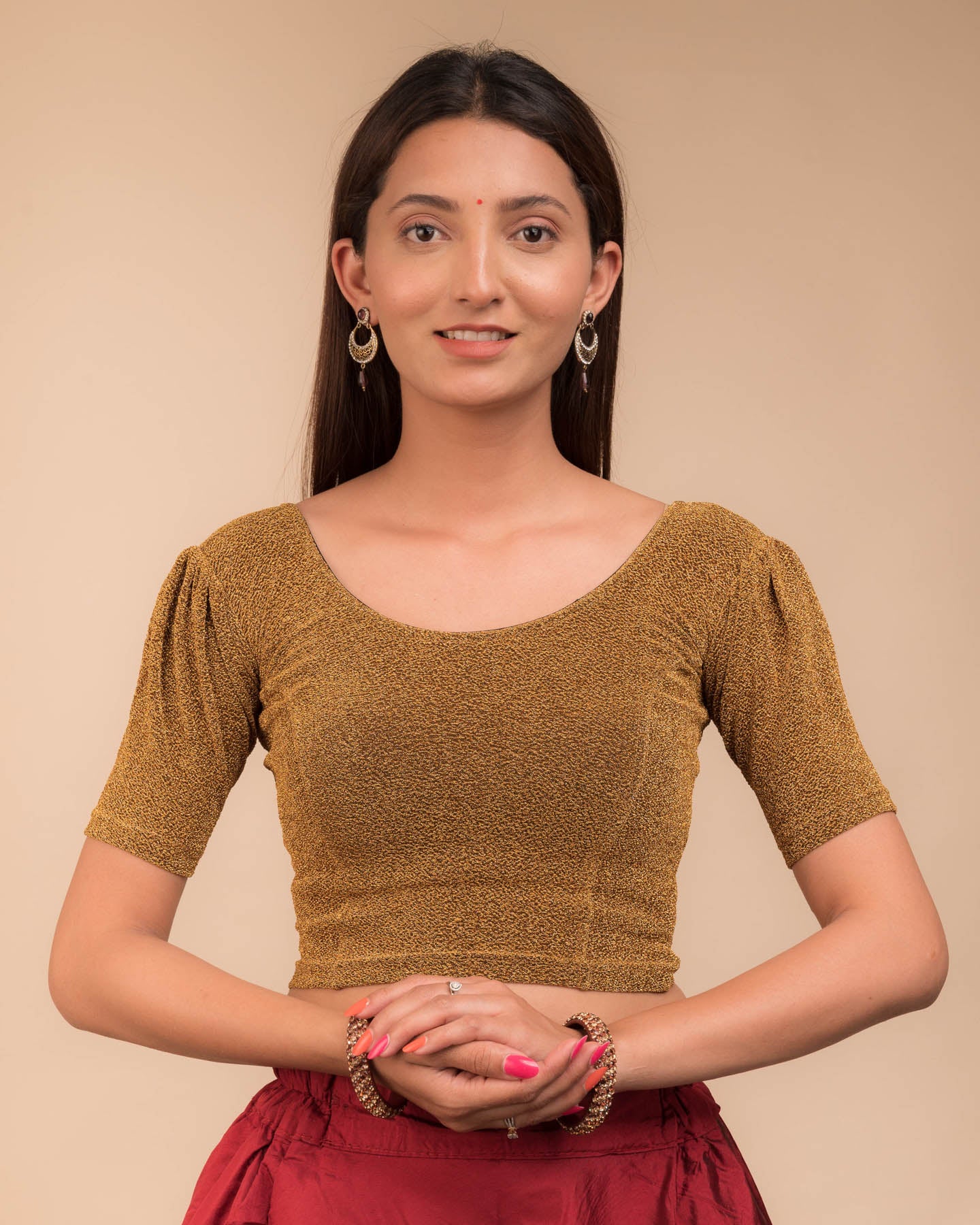 Model wearing a lustrous metallic stretchable blouse with pleated front and round neckline.