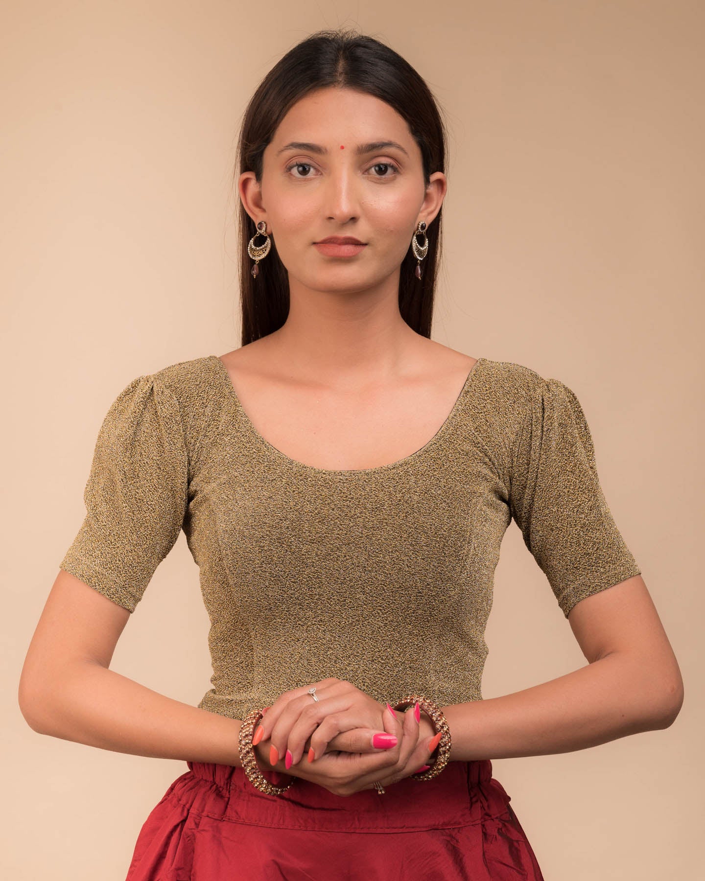 Model wearing a lustrous metallic stretchable blouse with pleated front and round neckline.