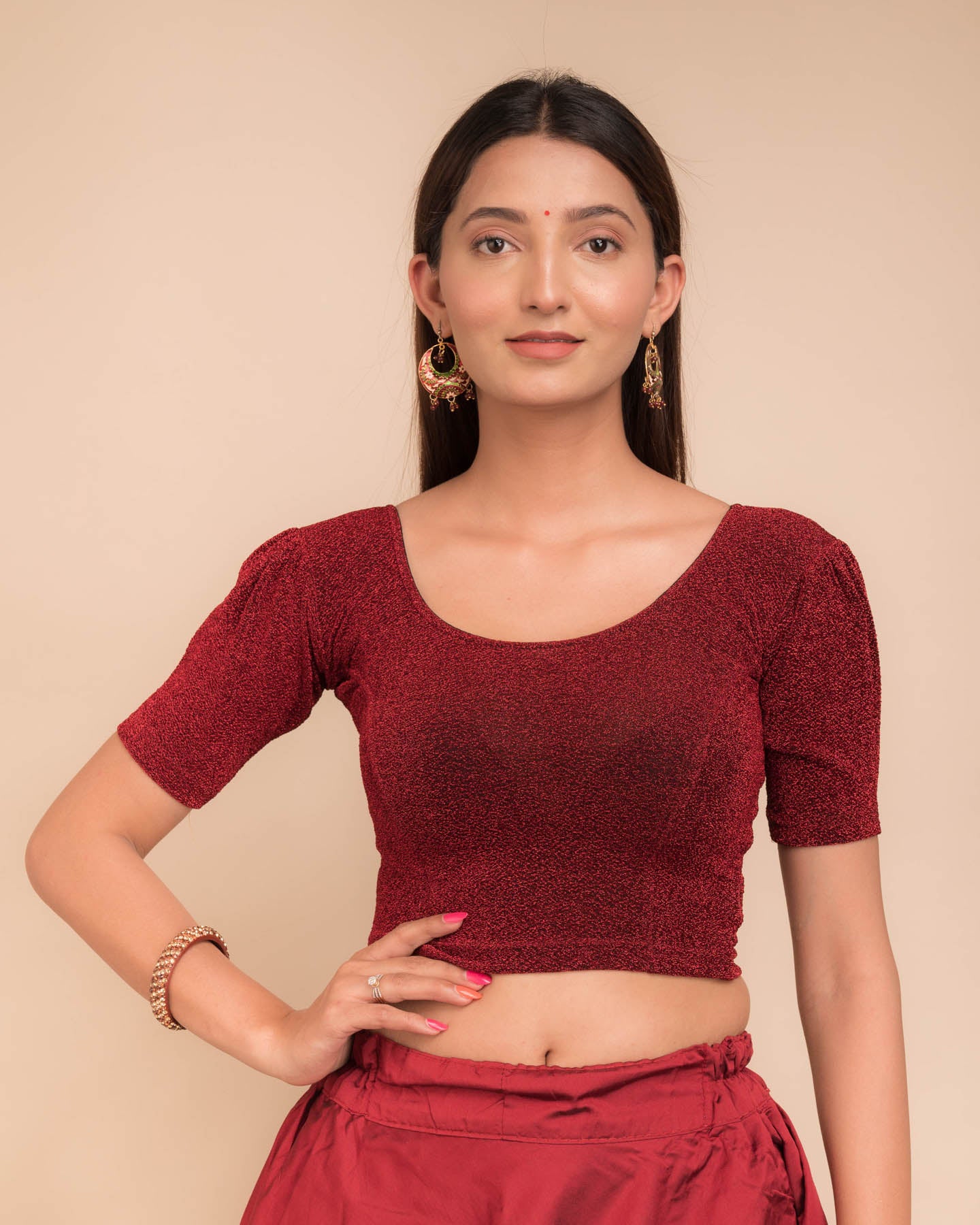 Model wearing a lustrous metallic stretchable blouse with pleated front and round neckline.