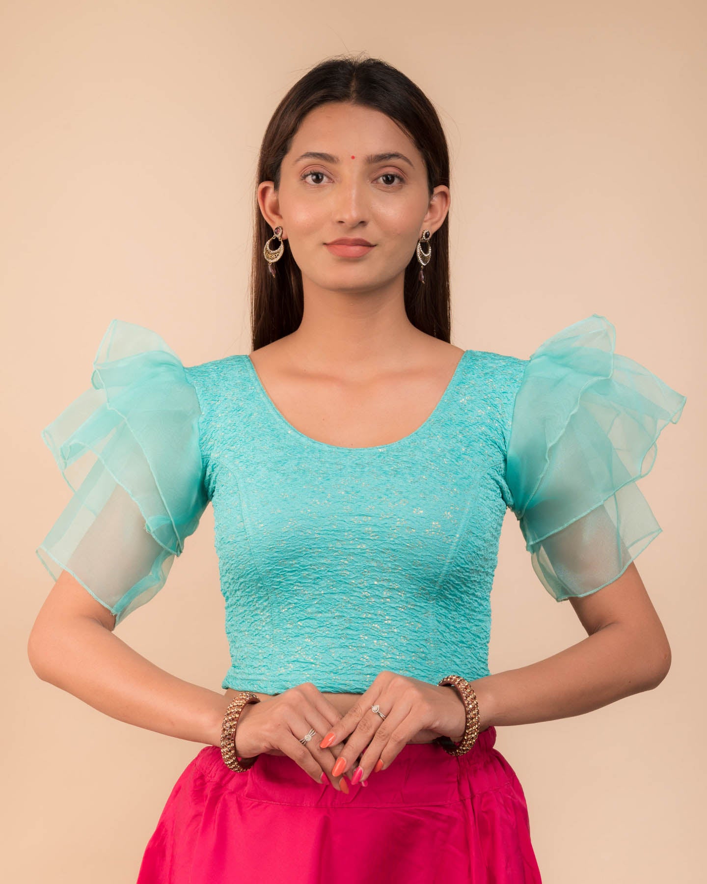 Model wearing an organza slip-on blouse with ruffled sleeves and round neckline
