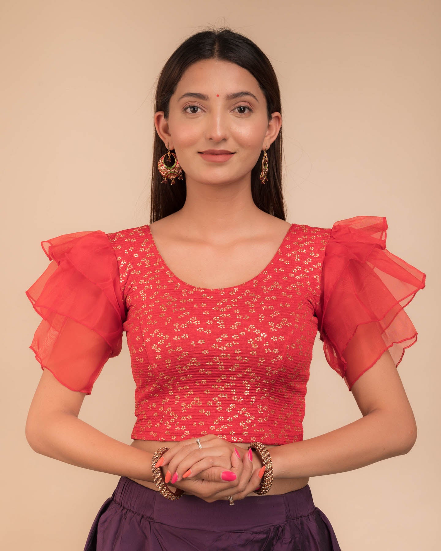 Model wearing an organza slip-on blouse with ruffled sleeves and round neckline