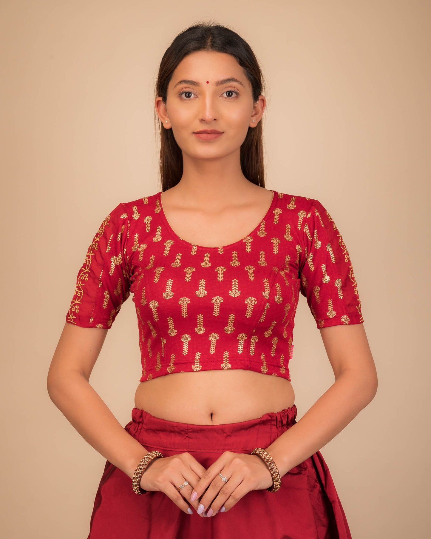 Model wearing a stretchable blouse with metallic gold print and zari embroidery, elbow sleeves, and round neckline