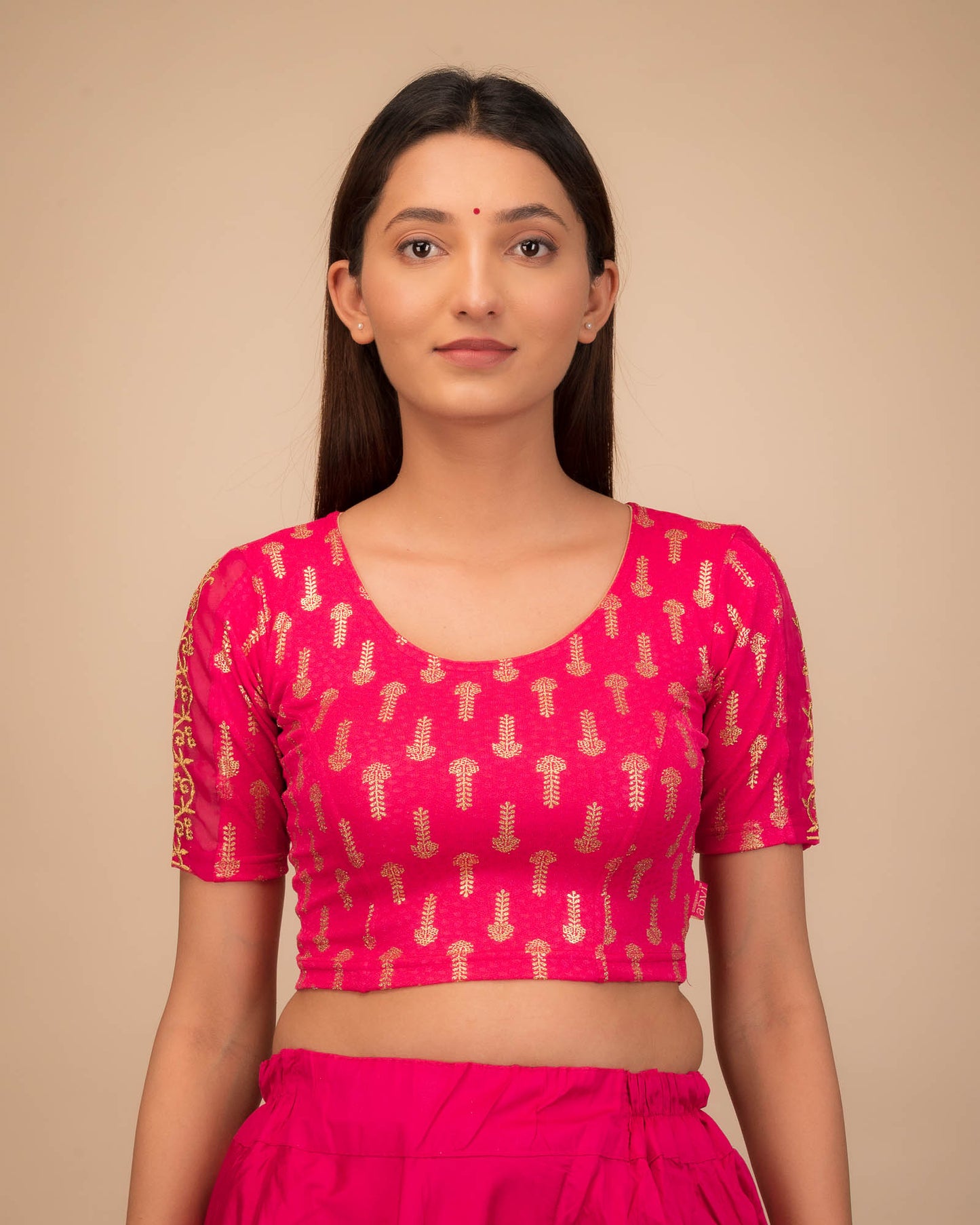 Model wearing a stretchable blouse with metallic gold print and zari embroidery, elbow sleeves, and round neckline