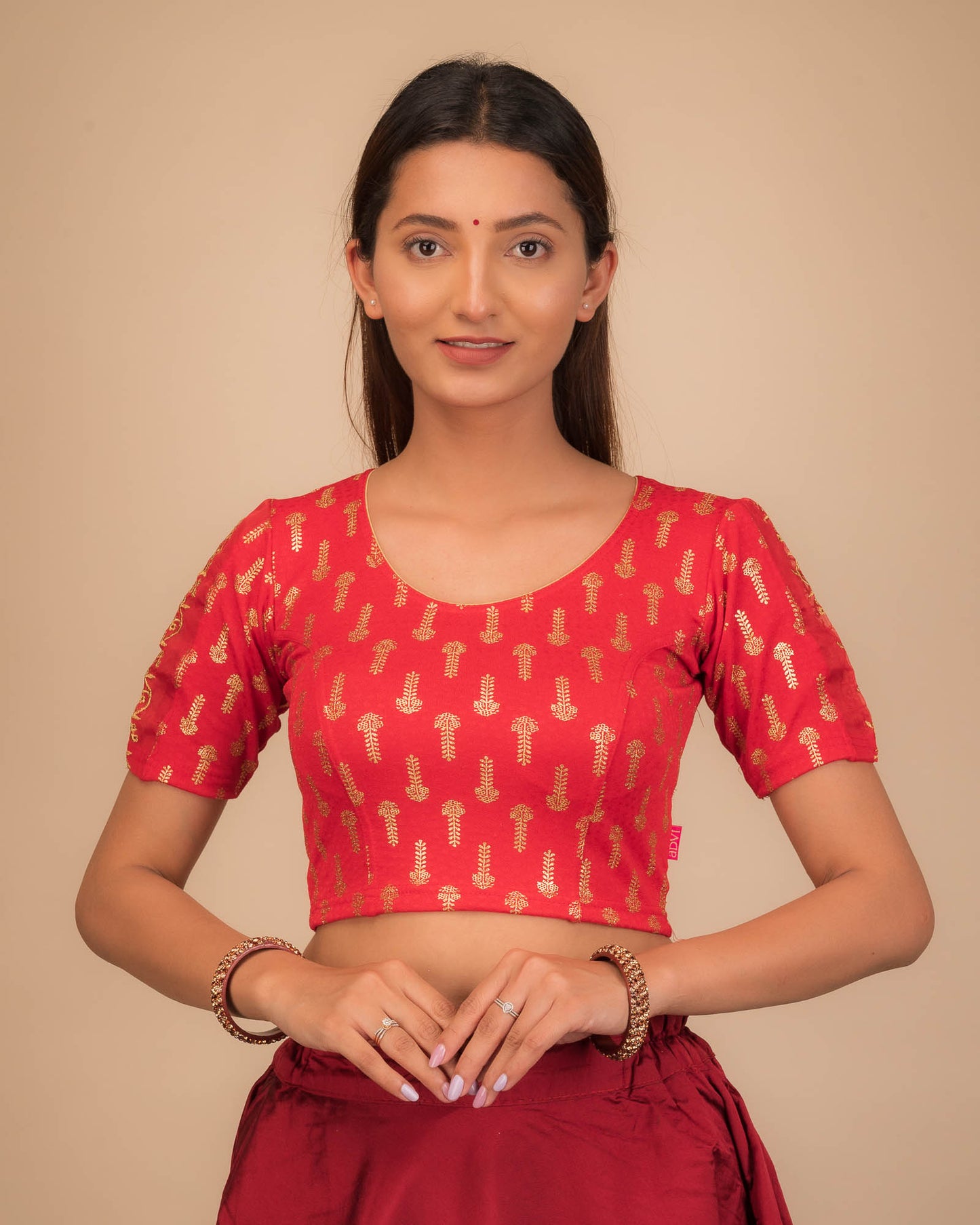 Model wearing a stretchable blouse with metallic gold print and zari embroidery, elbow sleeves, and round neckline