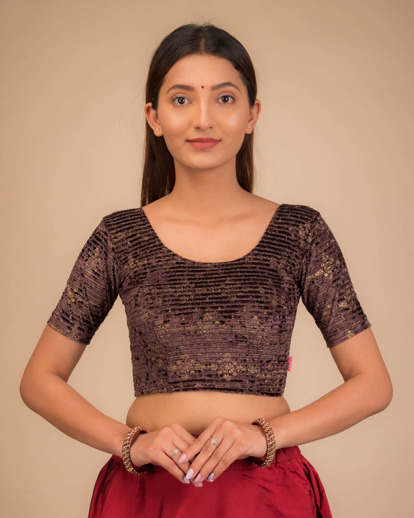 Model wearing a stretchable velvet blouse with elbow sleeves and round neckline.