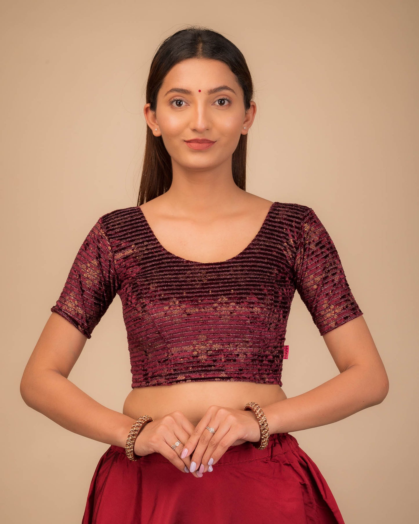 Model wearing a stretchable velvet blouse with elbow sleeves and round neckline.