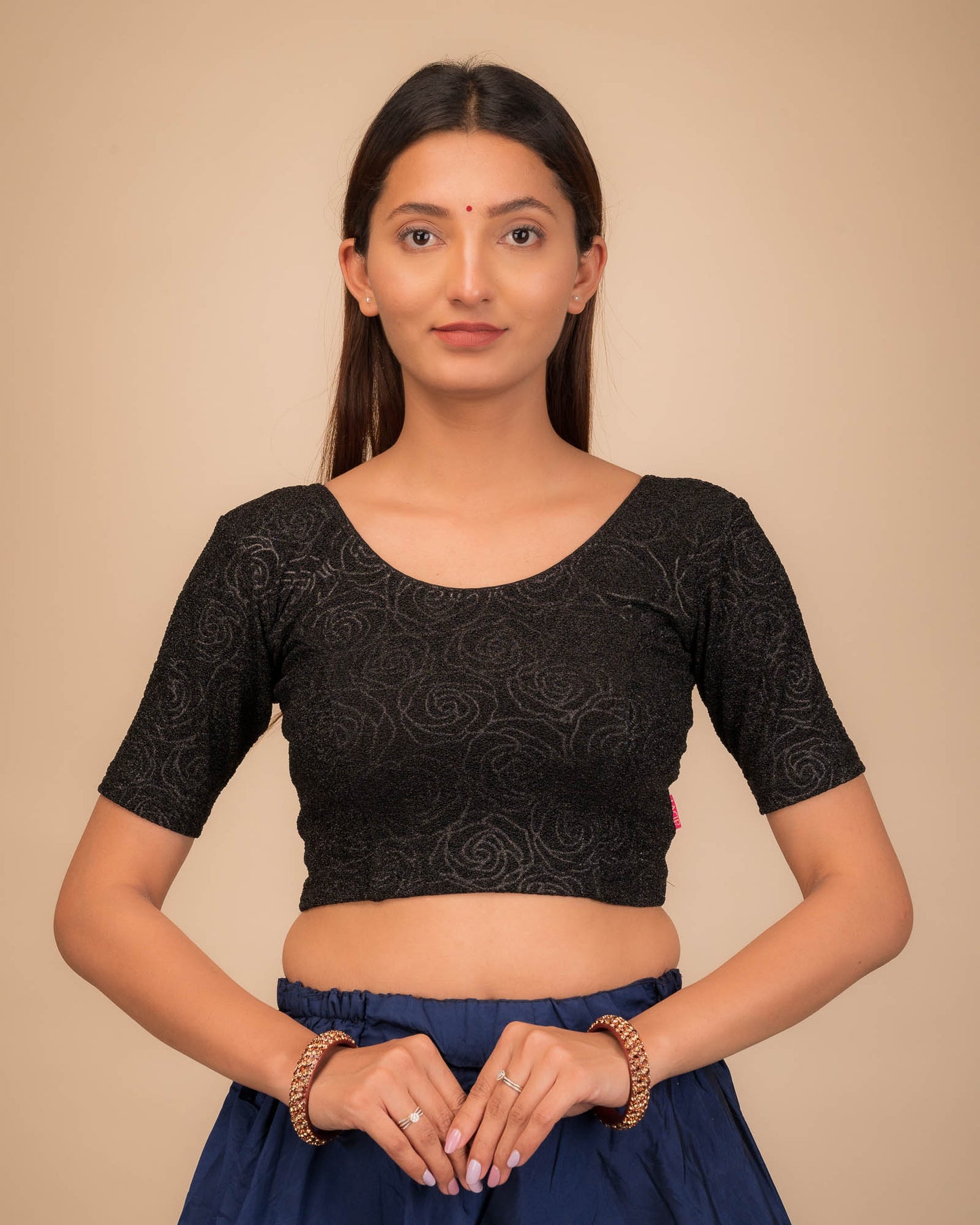 Model wearing a stretchable blouse with elbow sleeves and round neckline, featuring metallic emboss detailing.