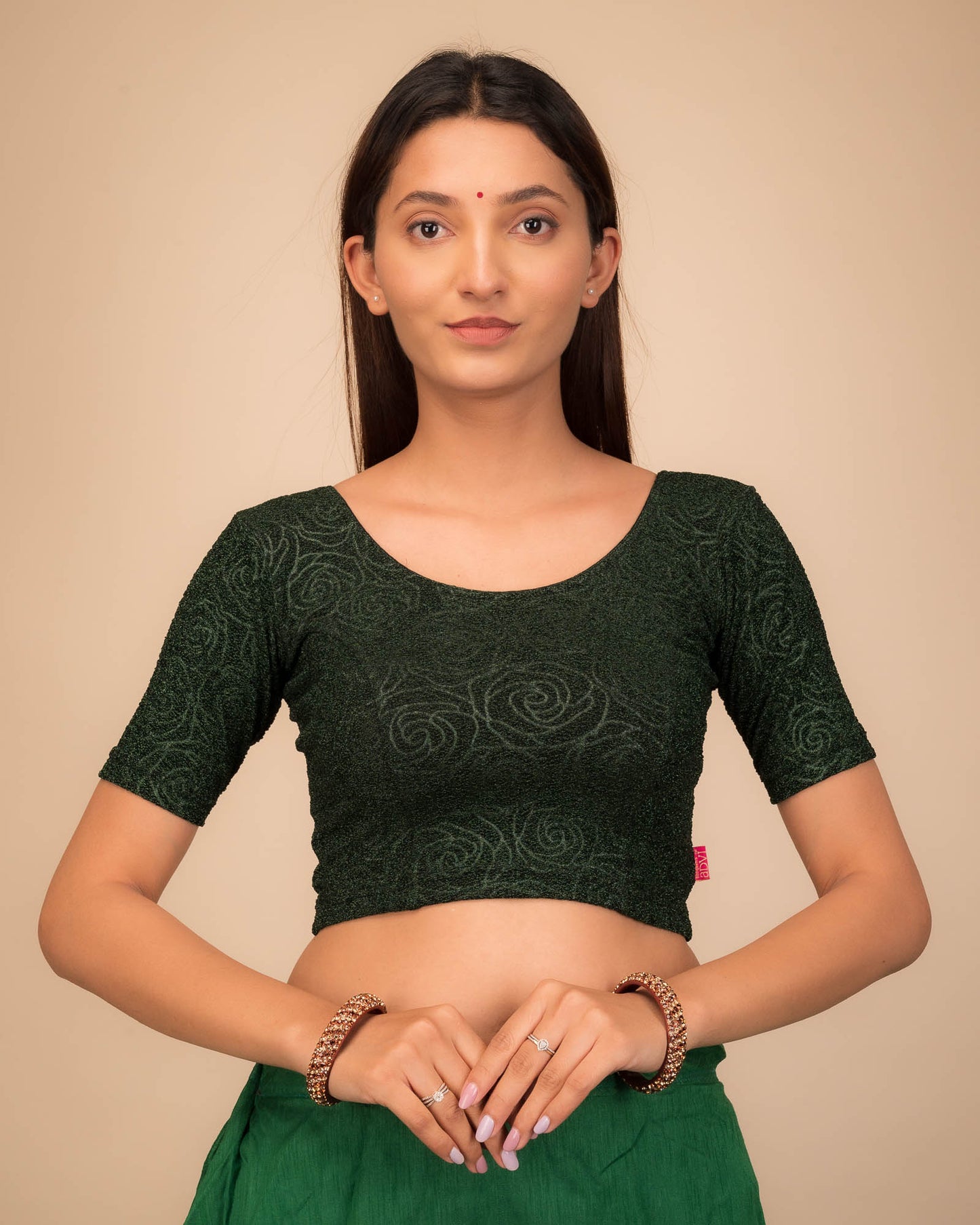 Model wearing a stretchable blouse with elbow sleeves and round neckline, featuring metallic emboss detailing.