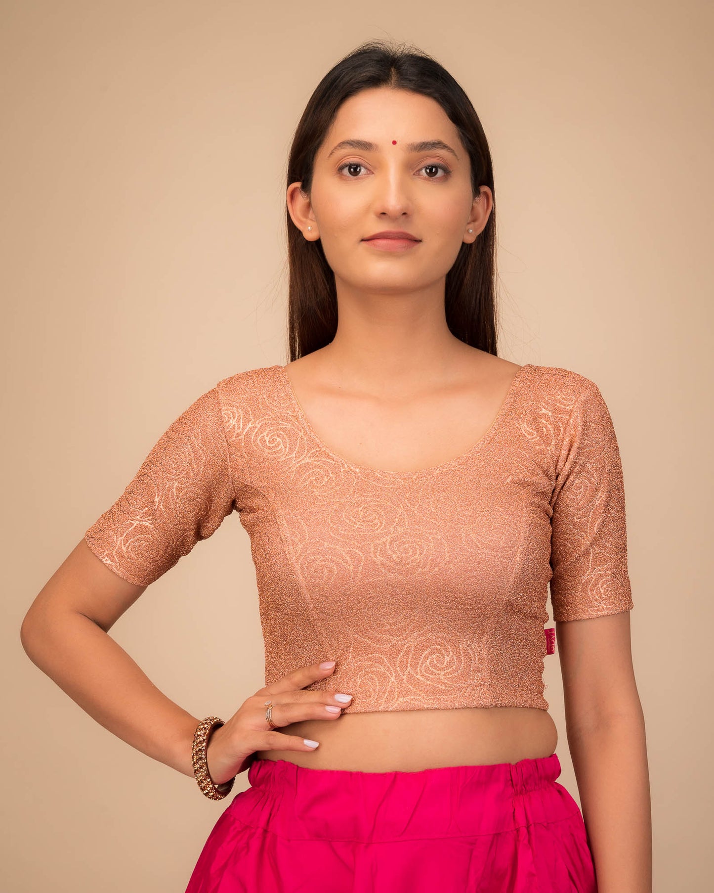 Model wearing a stretchable blouse with elbow sleeves and round neckline, featuring metallic emboss detailing.