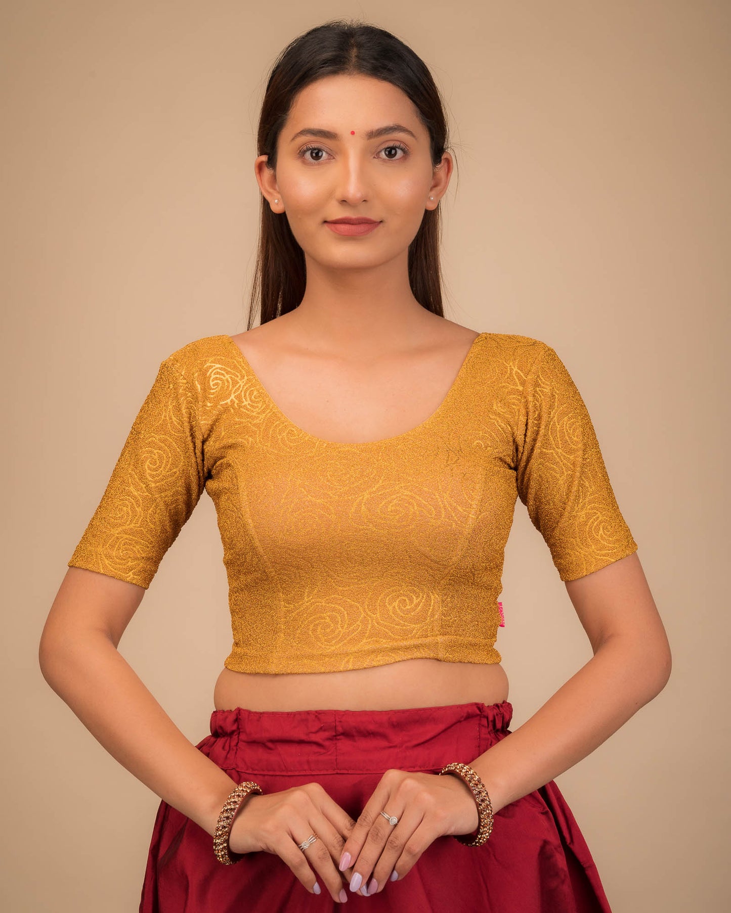 Model wearing a stretchable blouse with elbow sleeves and round neckline, featuring metallic emboss detailing.