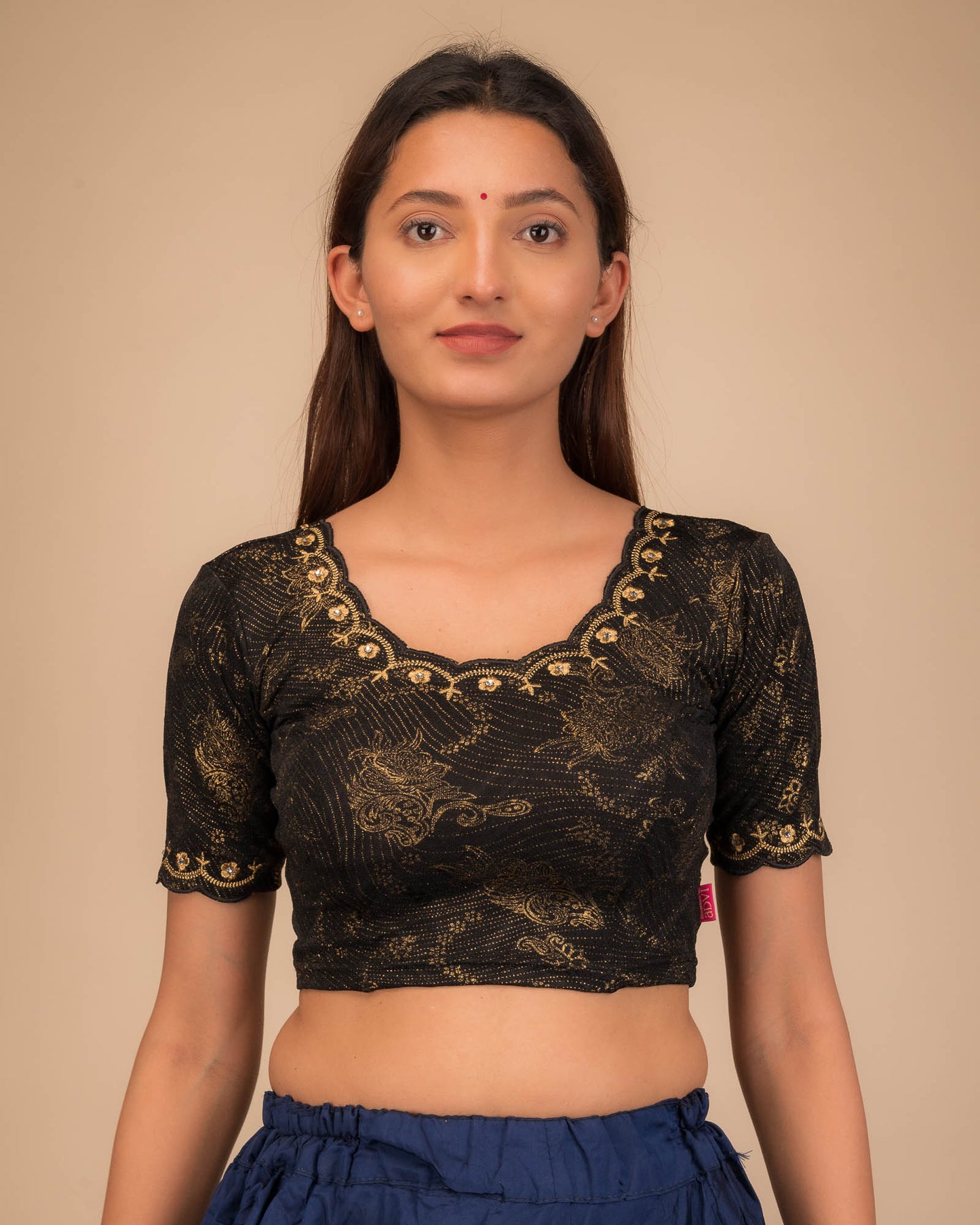 Model wearing a stretchable blouse with scalloped sleeves and round neckline featuring embroidery.