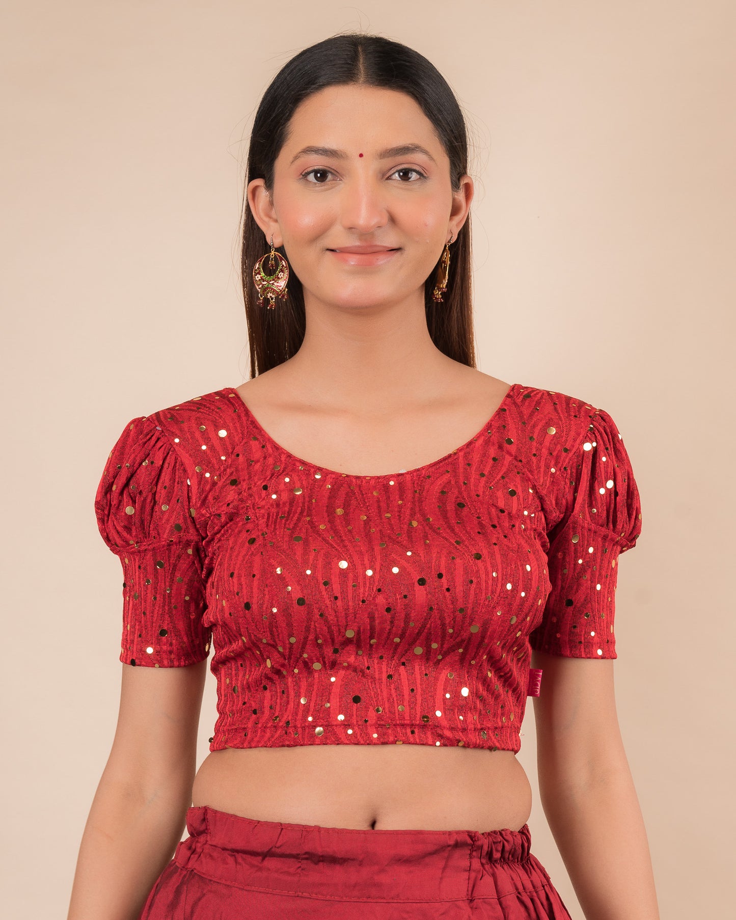 Model wearing a red stretchable blouse with gold mirror embellishments, puff sleeves, and round neckline