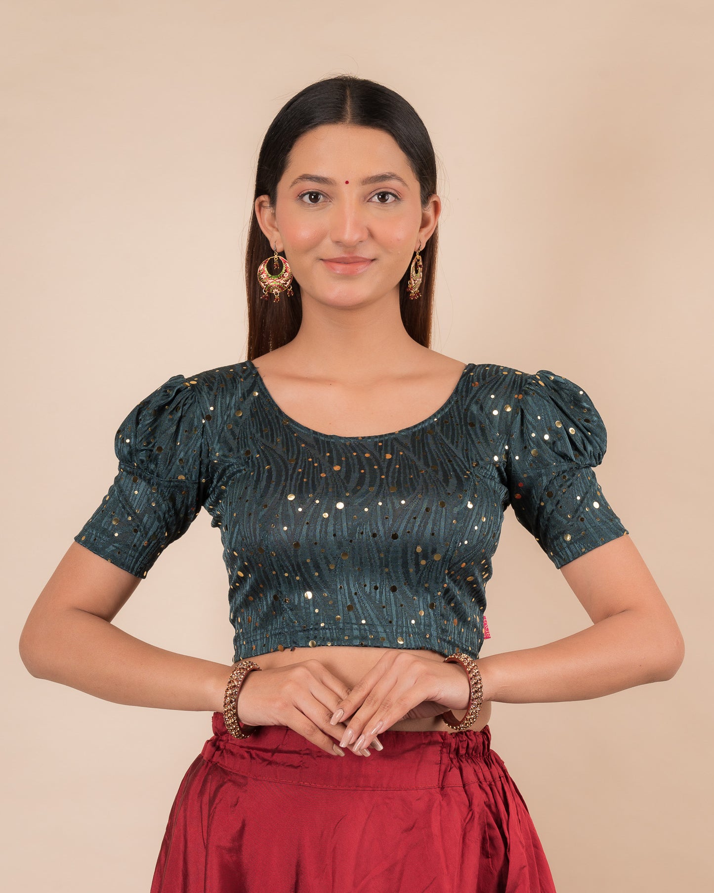 Model wearing a red stretchable blouse with gold mirror embellishments, puff sleeves, and round neckline