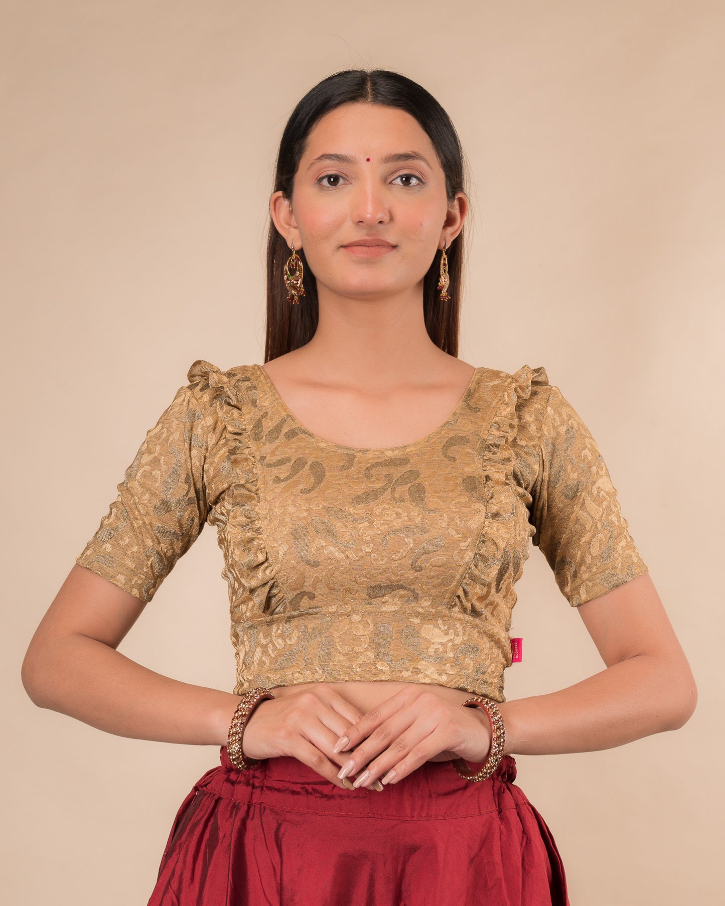 Model wearing an orange paisley paisley stretchable blouse with glitter, ruffled shoulders, elbow sleeves, and round neckline