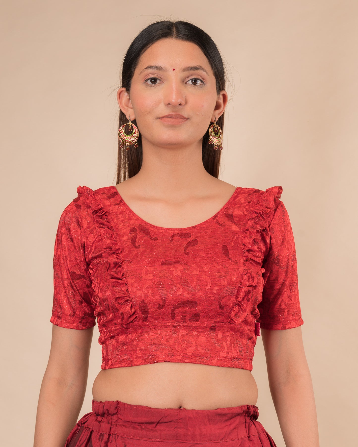 Model wearing an orange paisley paisley stretchable blouse with glitter, ruffled shoulders, elbow sleeves, and round neckline
