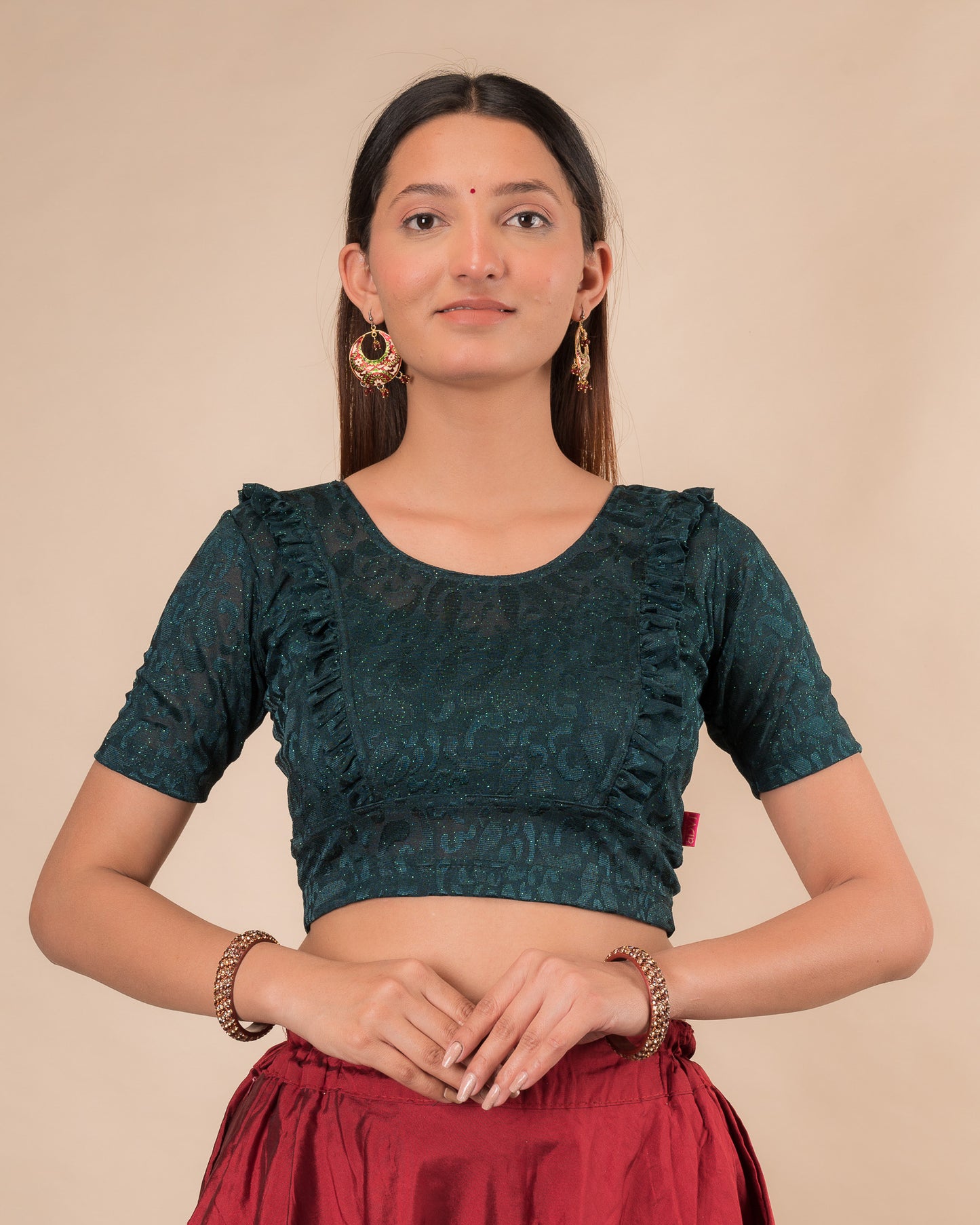 Model wearing an orange paisley paisley stretchable blouse with glitter, ruffled shoulders, elbow sleeves, and round neckline