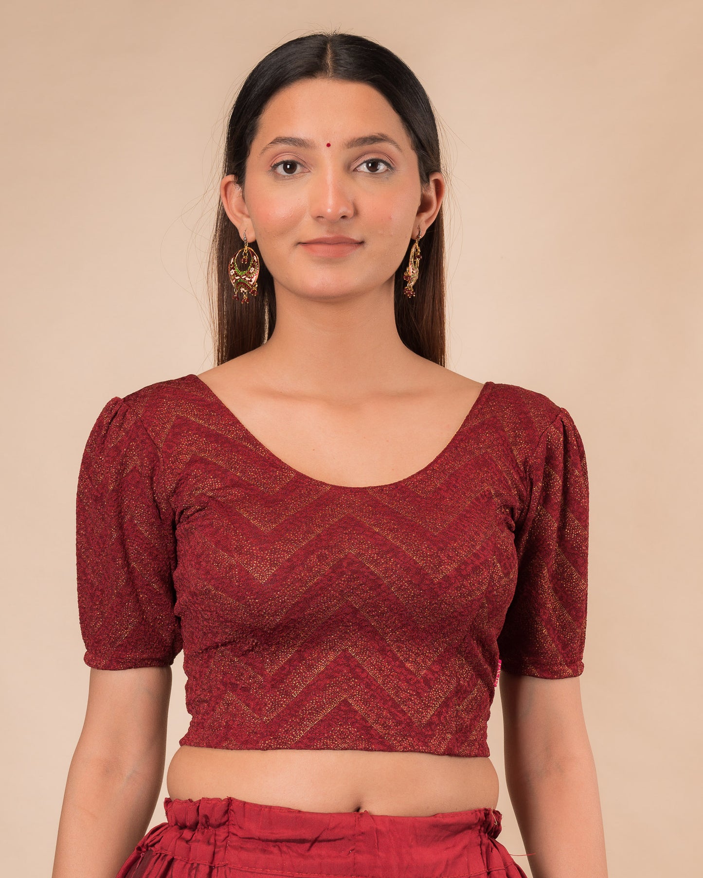 Model wearing an orange paisley paisley stretchable blouse with glitter, ruffled shoulders, elbow sleeves, and round neckline