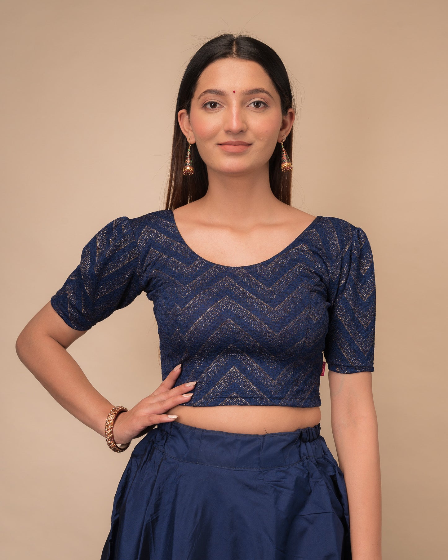 Model wearing an orange paisley paisley stretchable blouse with glitter, ruffled shoulders, elbow sleeves, and round neckline