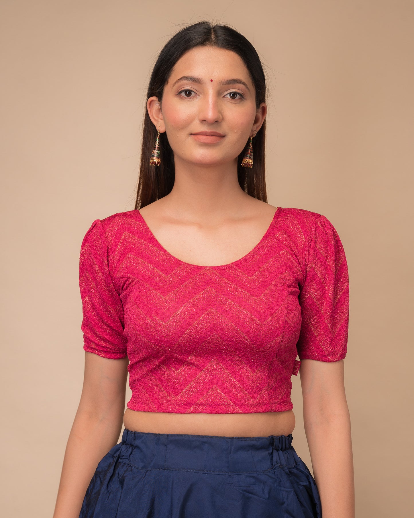 Model wearing an orange paisley paisley stretchable blouse with glitter, ruffled shoulders, elbow sleeves, and round neckline