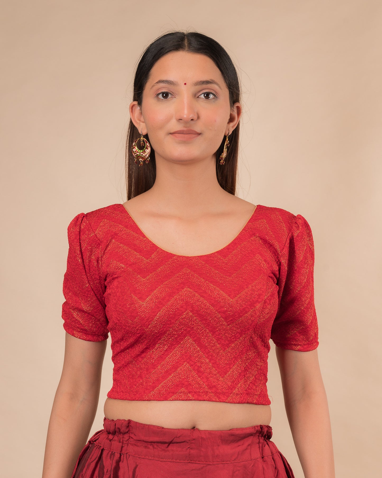 Model wearing an orange paisley paisley stretchable blouse with glitter, ruffled shoulders, elbow sleeves, and round neckline