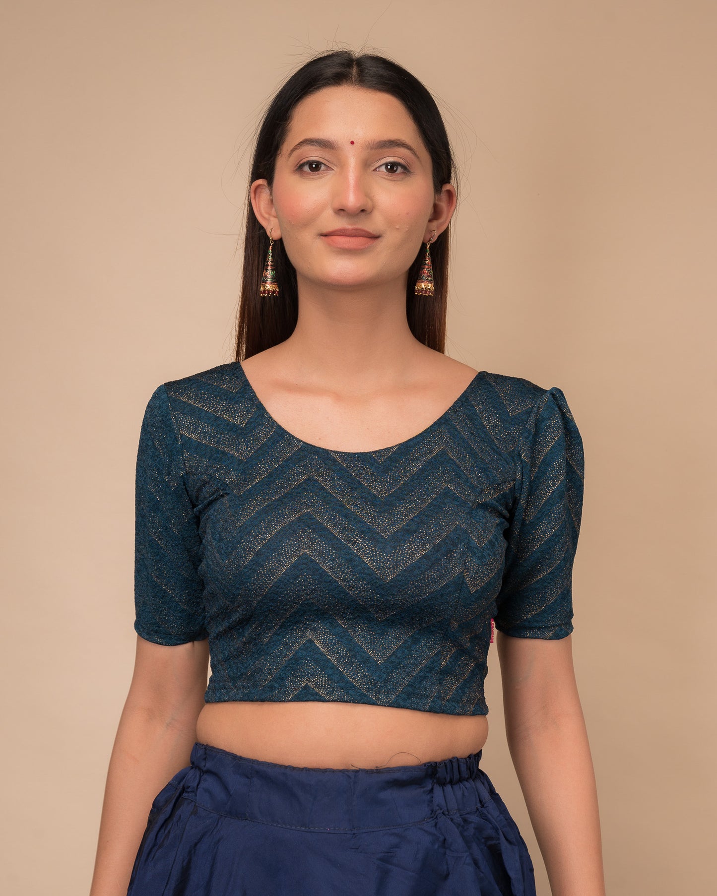 Model wearing an orange paisley paisley stretchable blouse with glitter, ruffled shoulders, elbow sleeves, and round neckline
