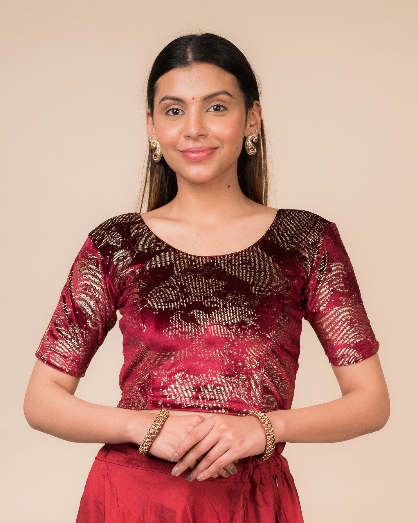 Model wearing a maroon velvet stretchable blouse with gold paisley prints, elbow sleeves, and round neckline.