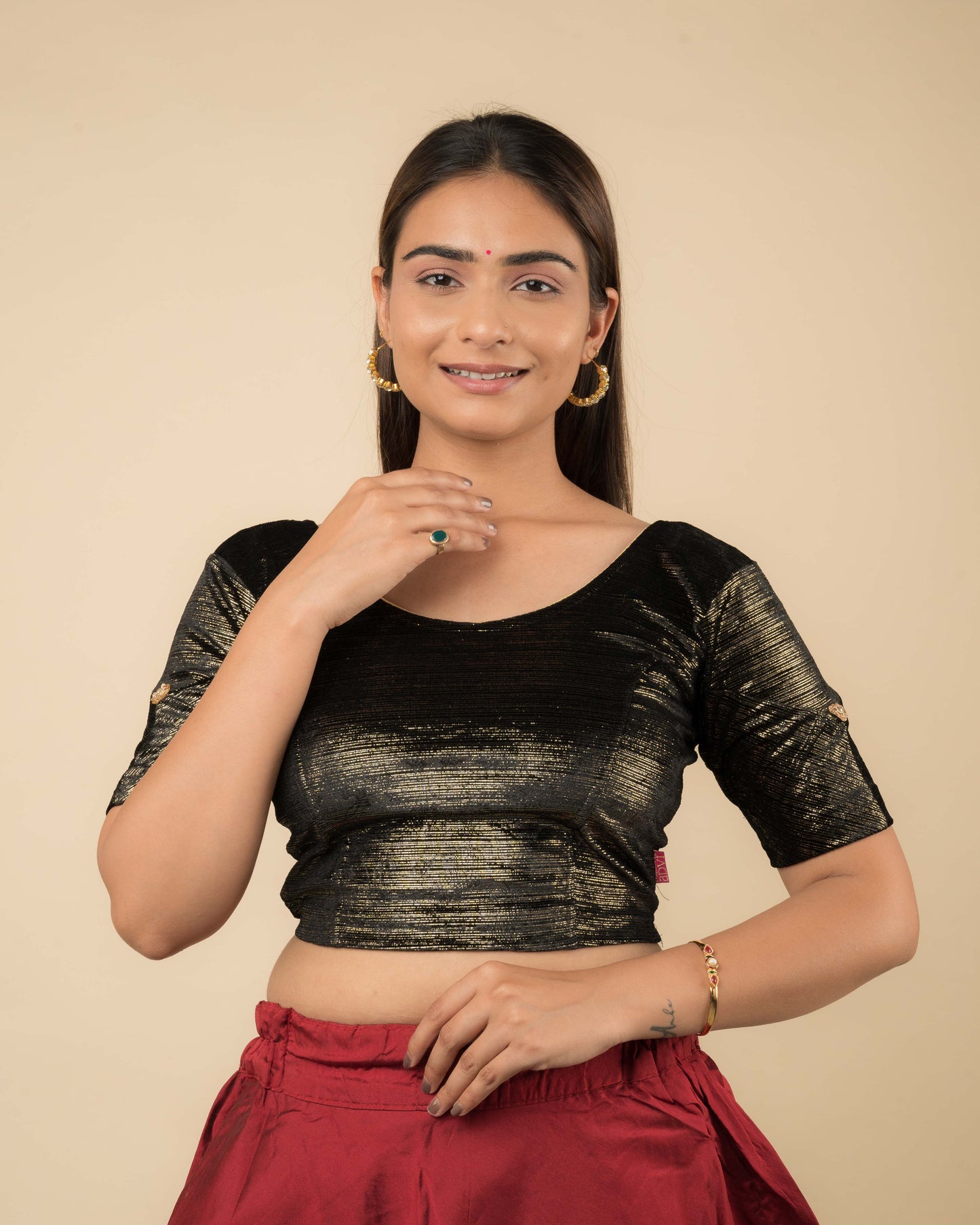 Model wearing a velvet blouse with gold buti and stripes, elbow sleeves, and round neckline