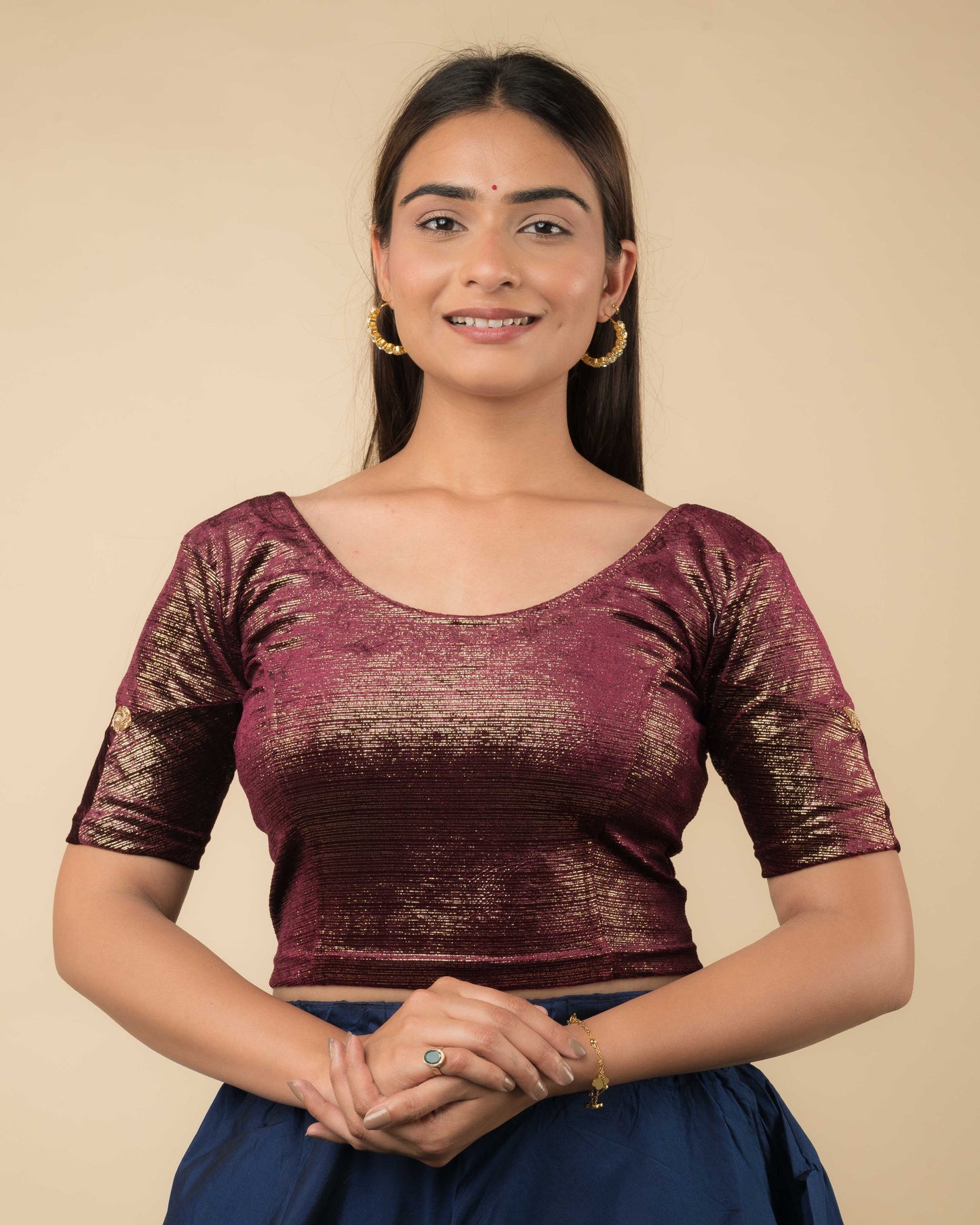 Model wearing a maroon velvet blouse with gold buti and stripes, elbow sleeves, and round neckline