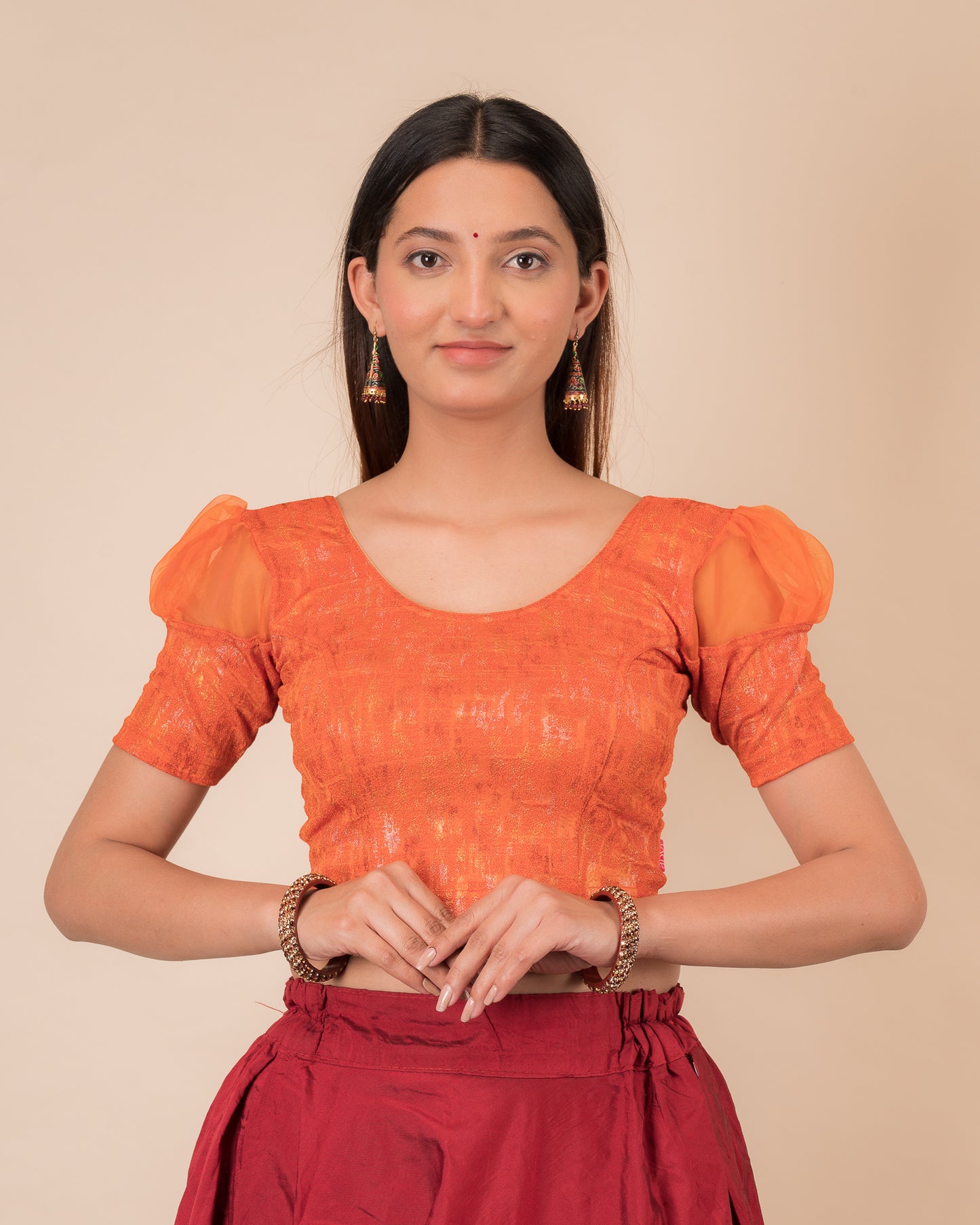 Model wearing a stretchable foil-textured blouse with sheer puff sleeves and round neckline
