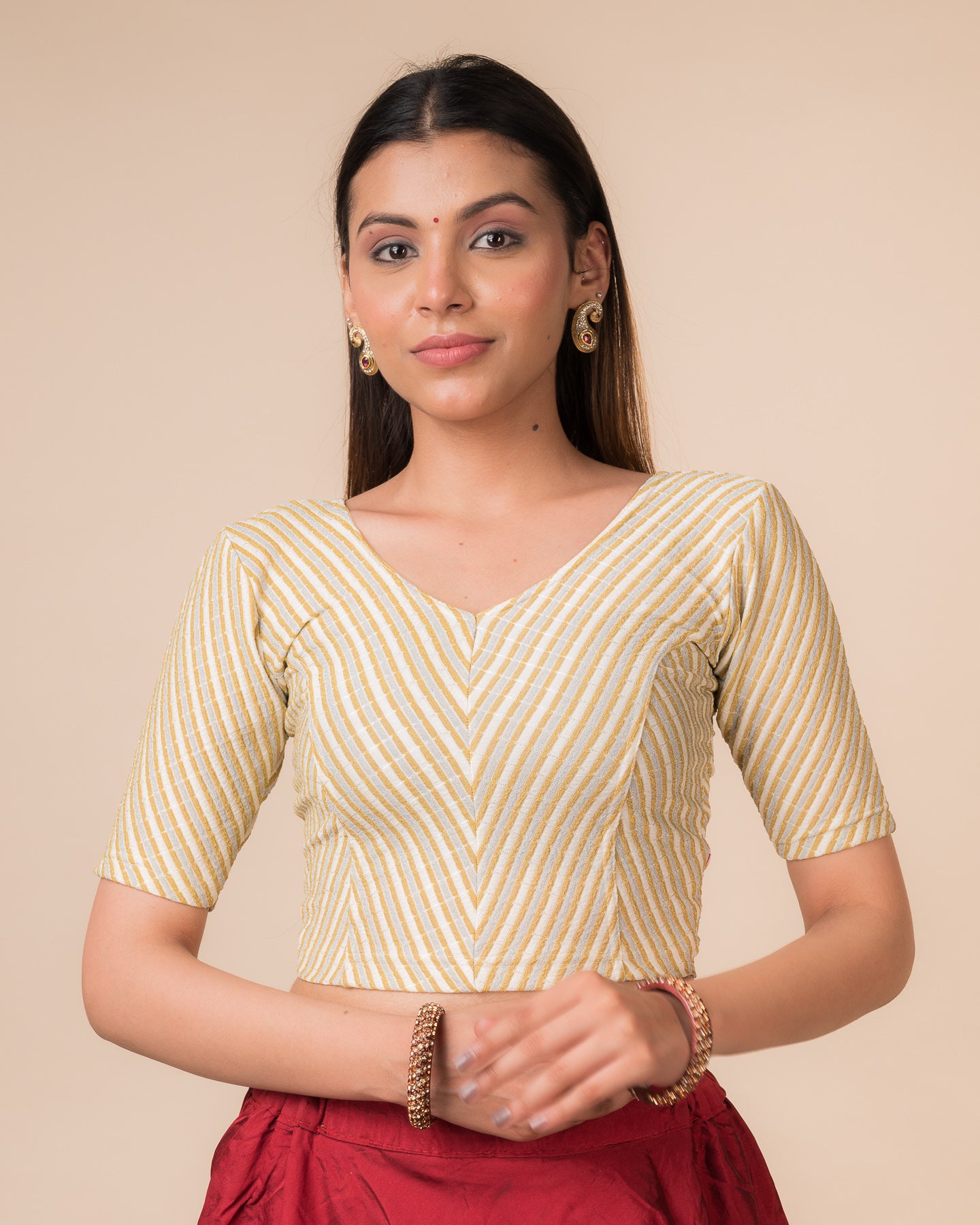 Model wearing a cream gold zari stretchable readymade blouse with elbow sleeves and V-neckline.