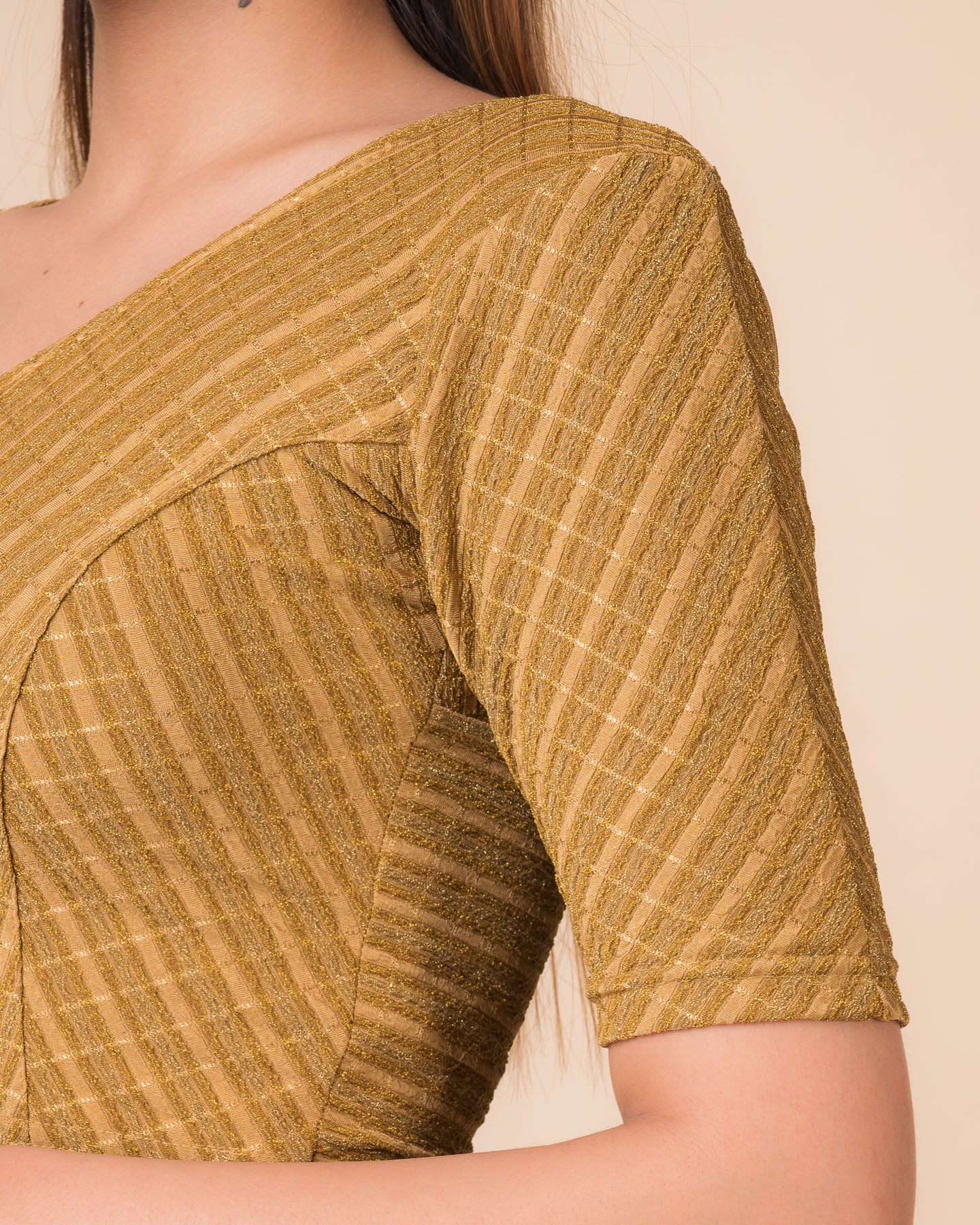 Close-up of the dark gold zari fabric detailing the texture and stretchability of the readymade blouse.