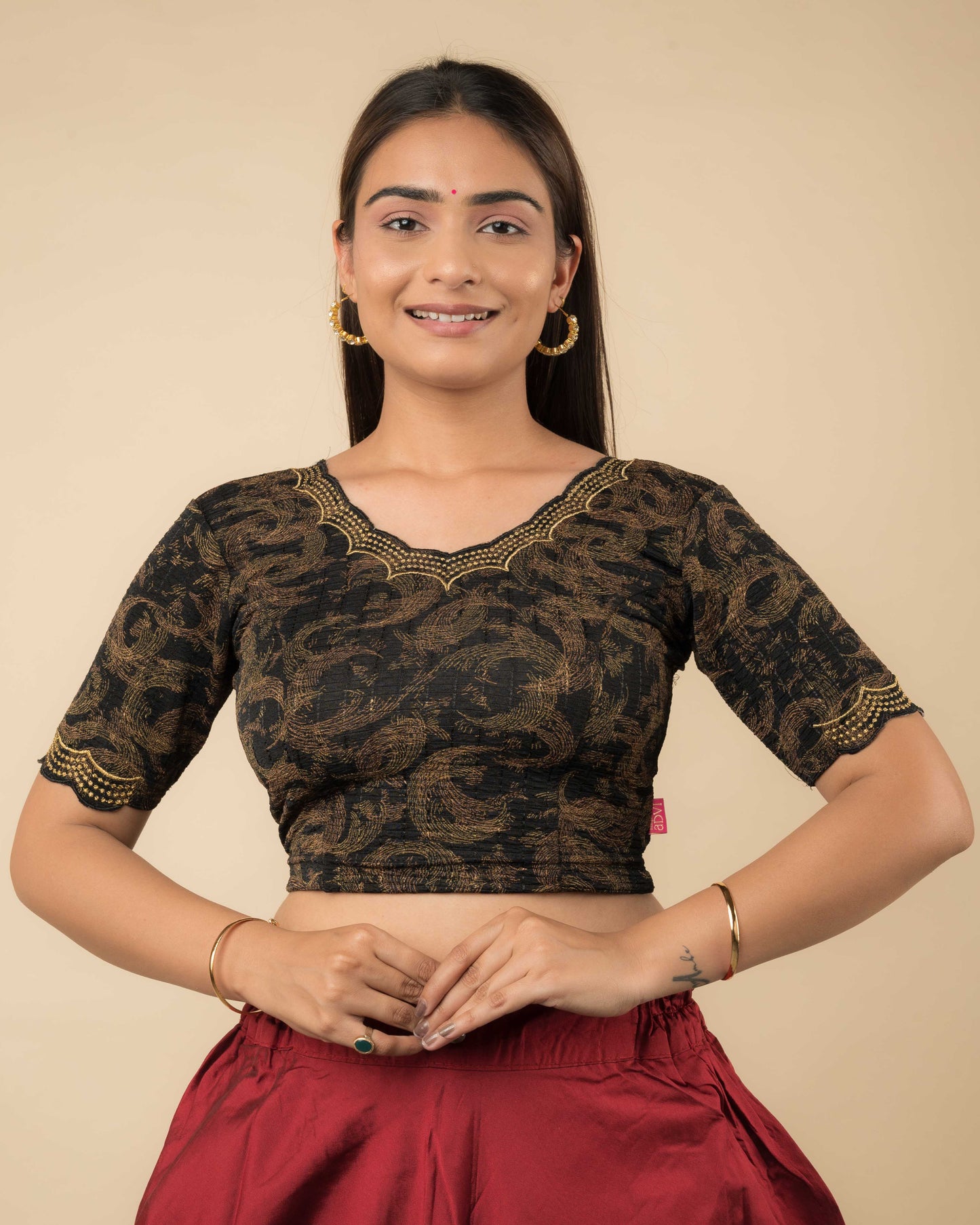 Model wearing a Black-colored stretchable readymade blouse with zari embroidery, elbow sleeves, and scalloped round neckline.