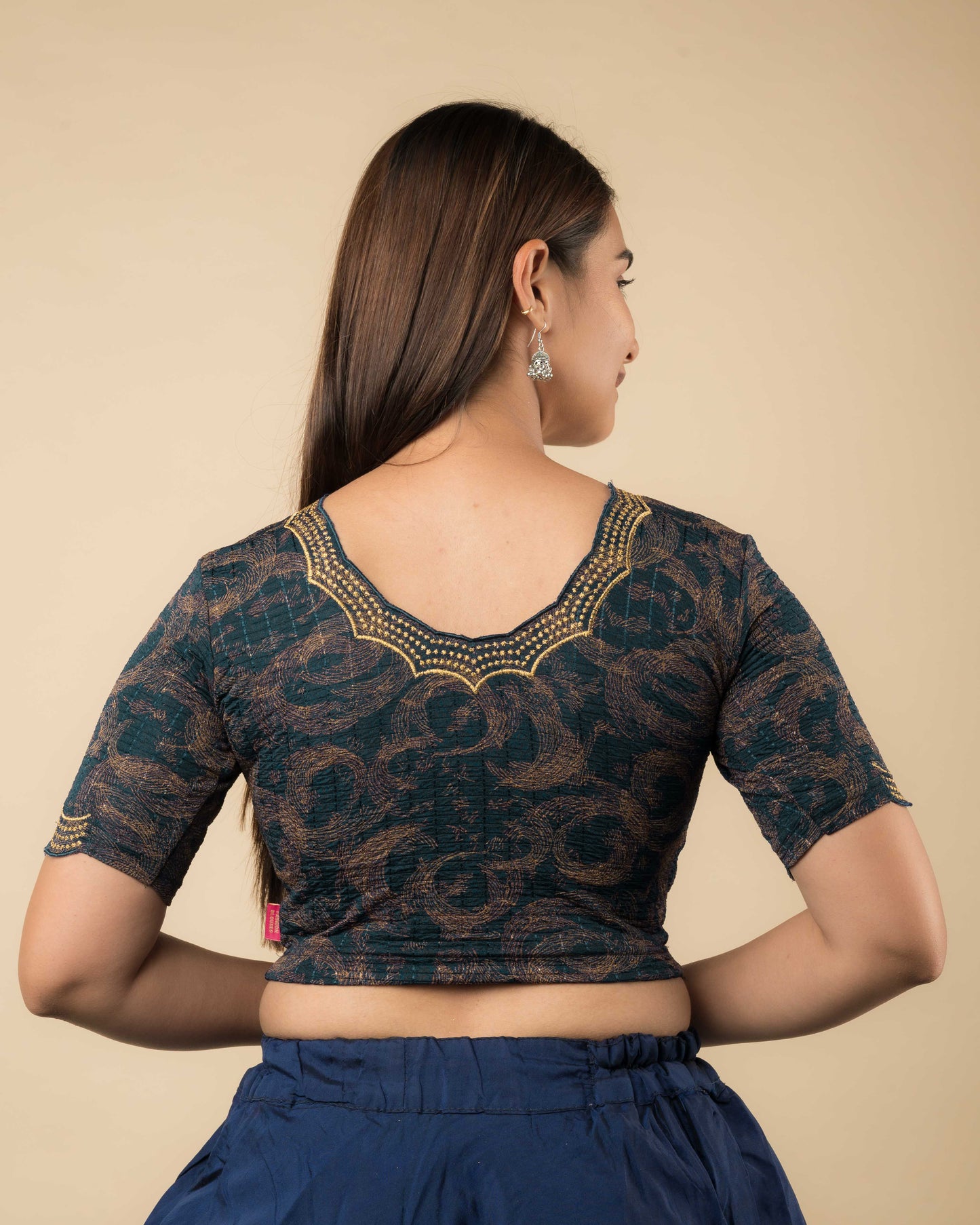 Rear view of the bottle green-colored stretchable blouse showcasing the back design and zari embroidery.