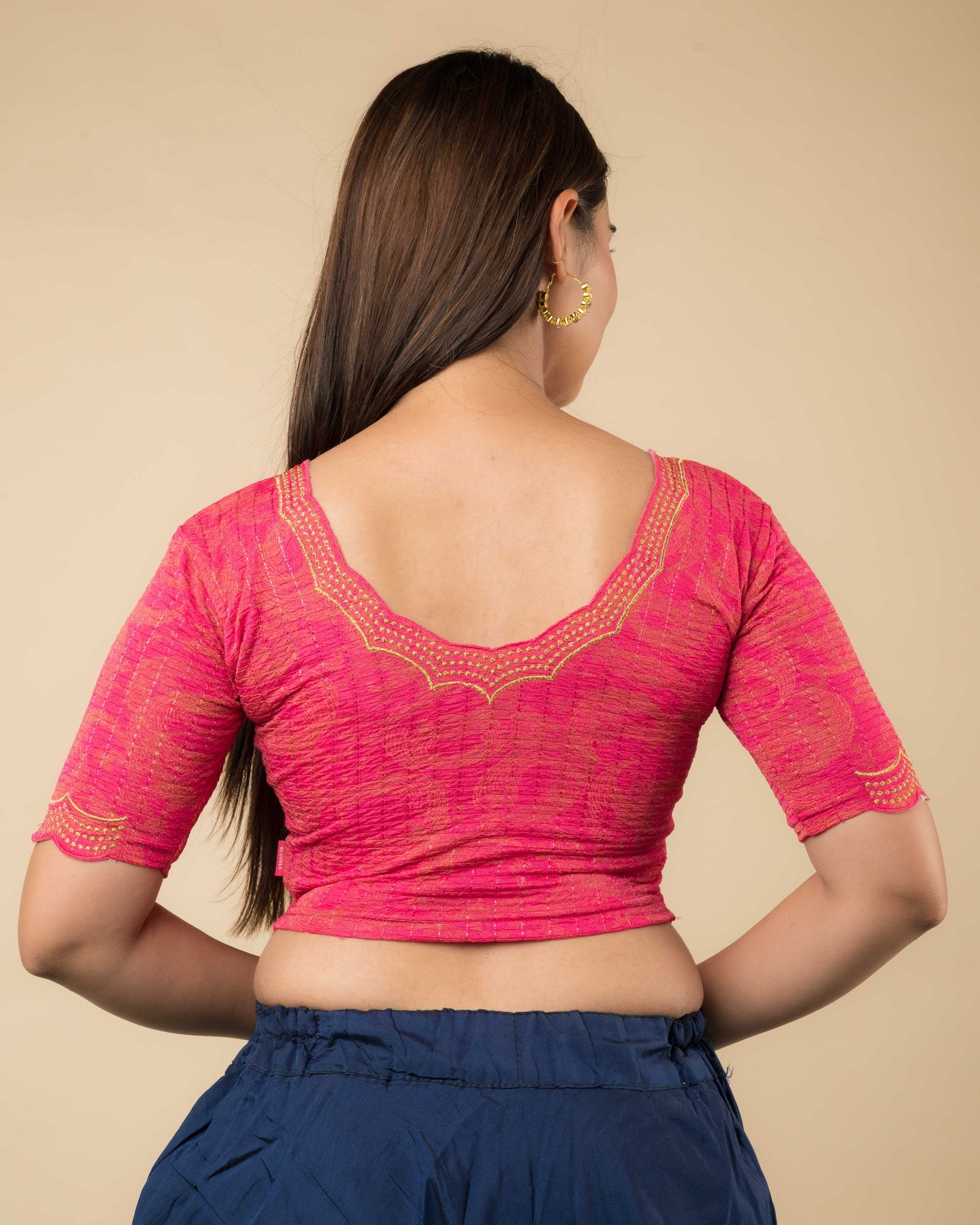 Rear view of the rani-colored stretchable blouse showcasing the back design and zari embroidery.