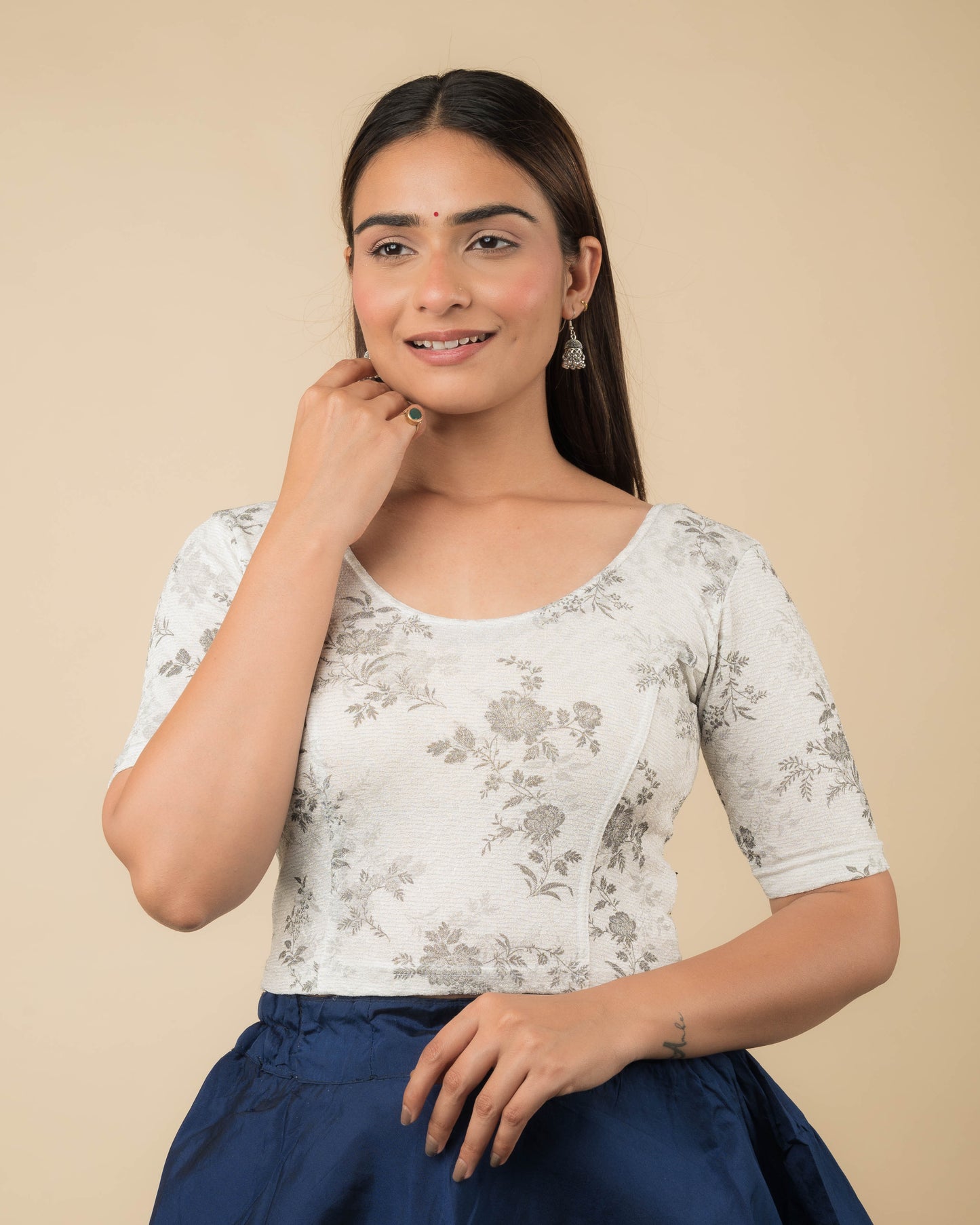 Model wearing a metallic floral stretchable readymade blouse with elbow sleeves and round neckline.