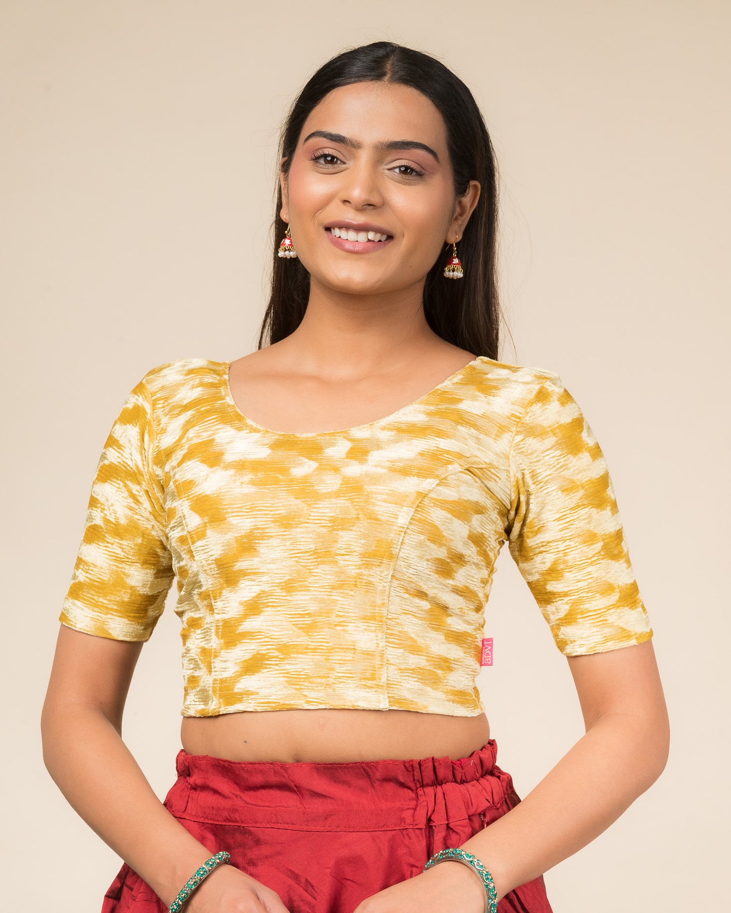 Model wearing a zari embellished velvet stretchable readymade blouse with elbow sleeves and round neckline.