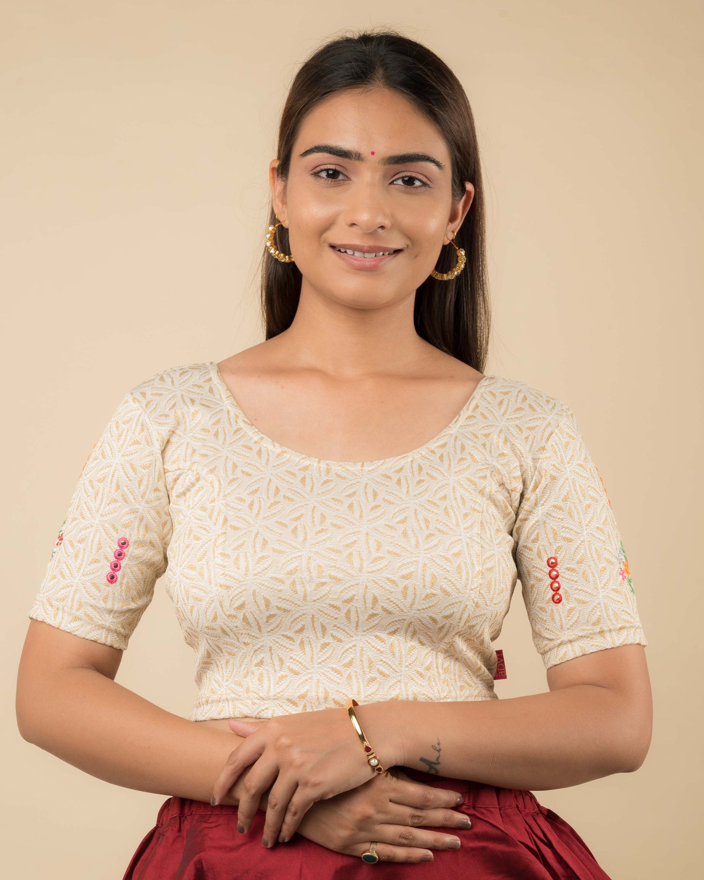 Model wearing a mirror embellished knitted stretchable readymade blouse with elbow sleeves and round neckline.