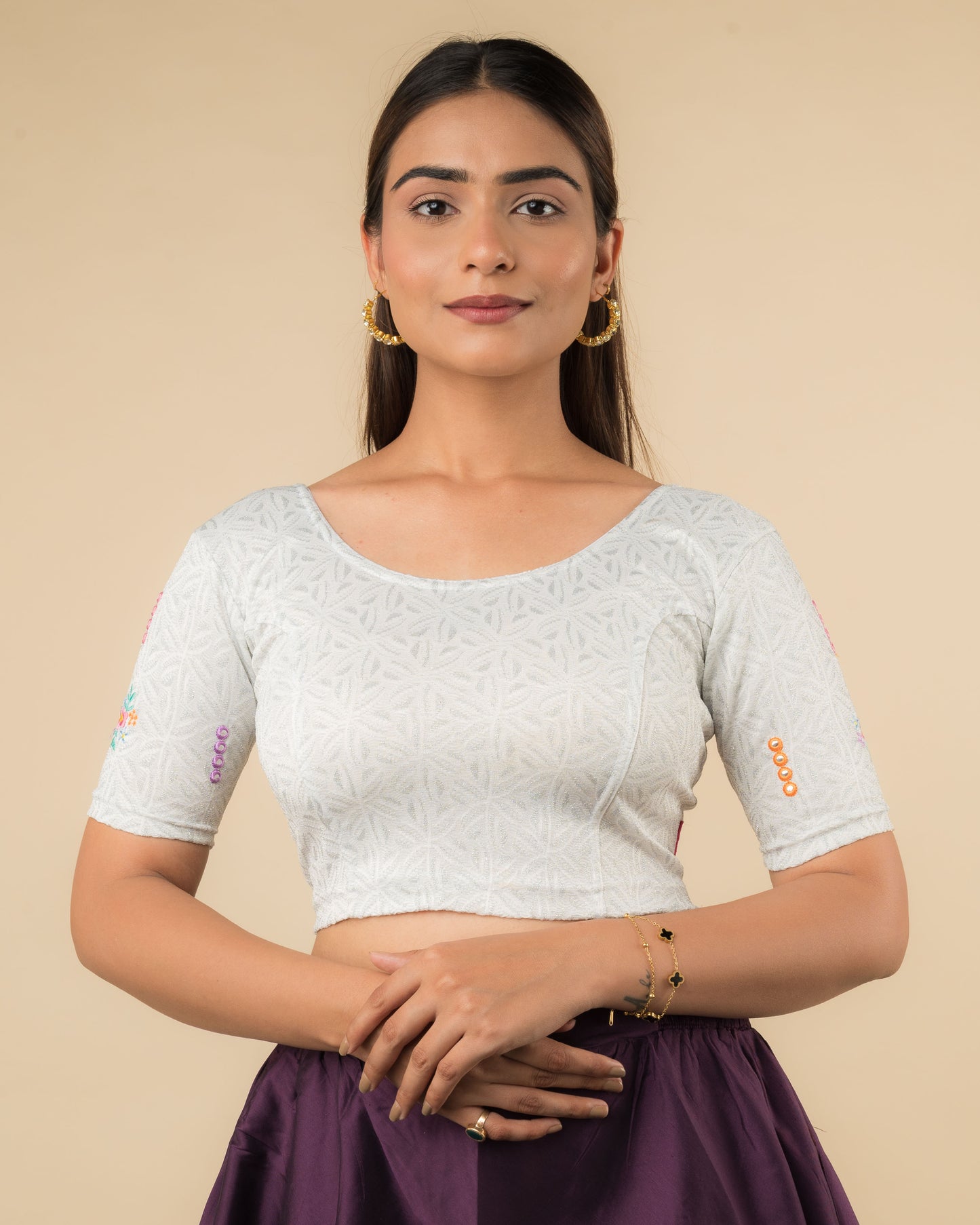Model wearing a mirror embellished knitted stretchable readymade blouse with elbow sleeves and round neckline.
