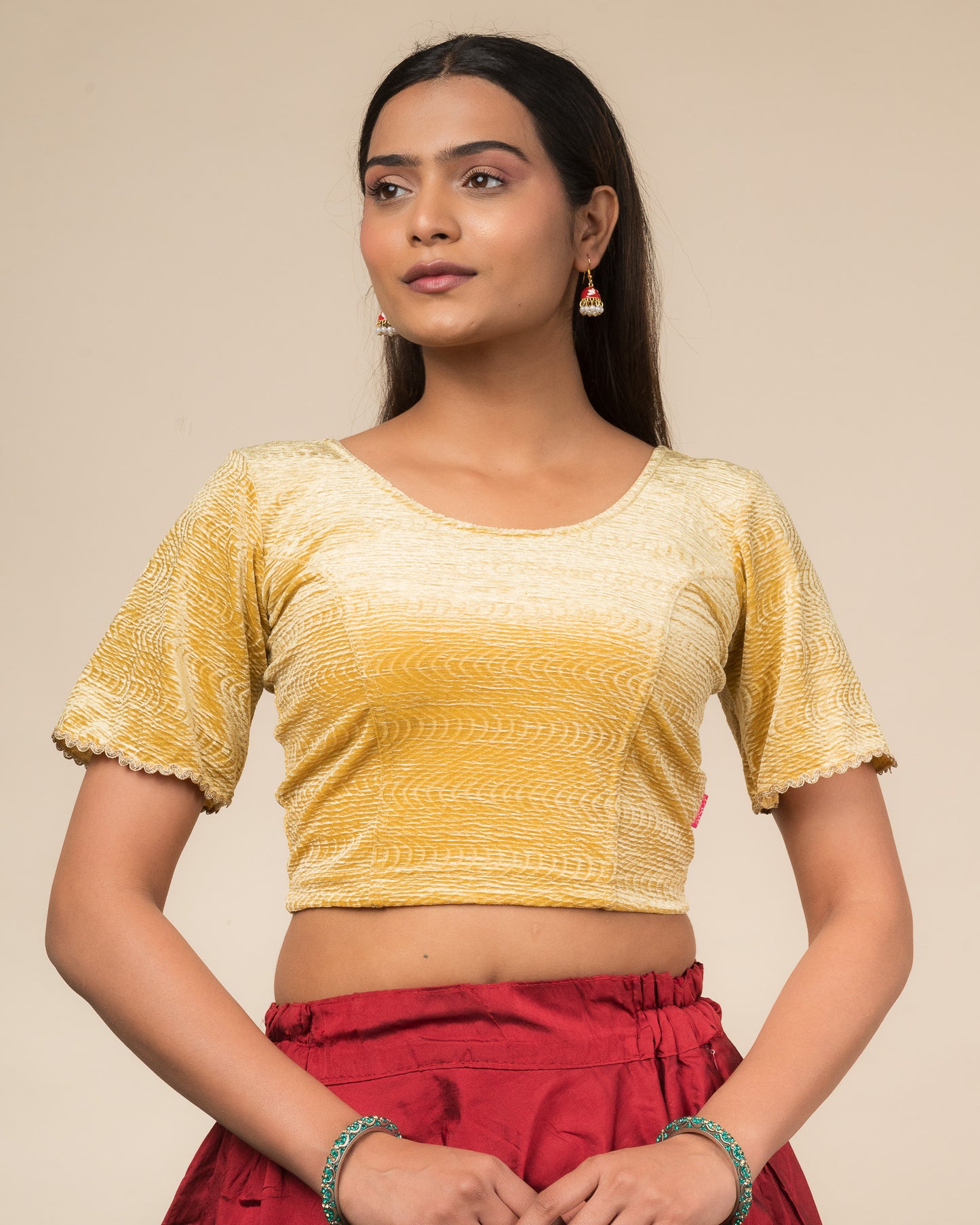 Model wearing a velvet stretchable readymade blouse with elbow-length bell sleeves and round neckline.