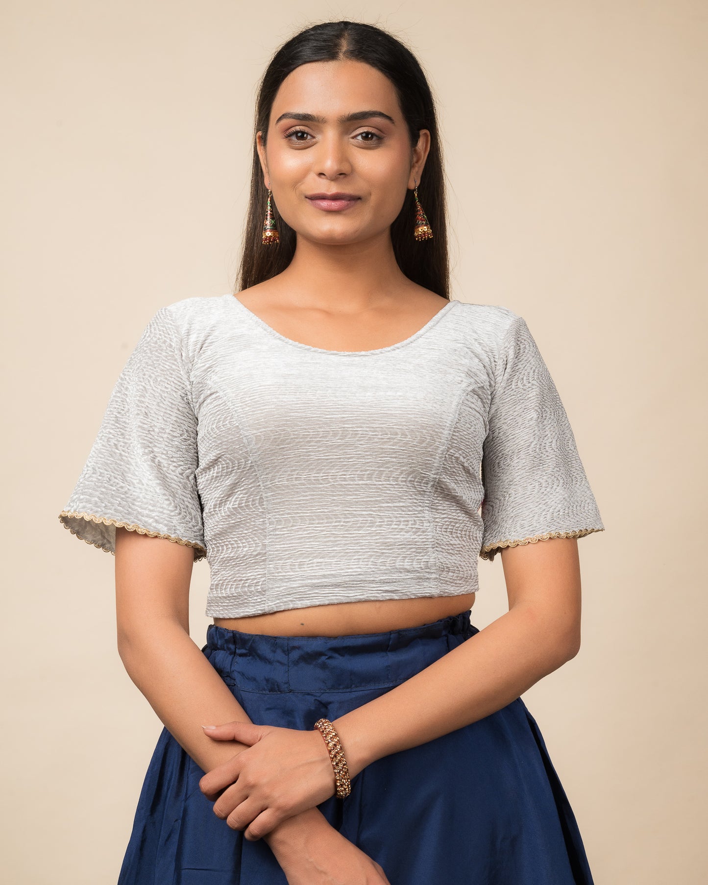 Model wearing a velvet stretchable readymade blouse with elbow-length bell sleeves and round neckline.
