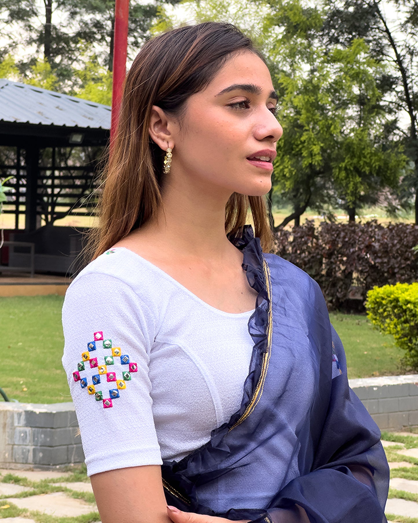 Model wearing a stretchable blouse with mirror embroidery on the neckline and sleeves.
