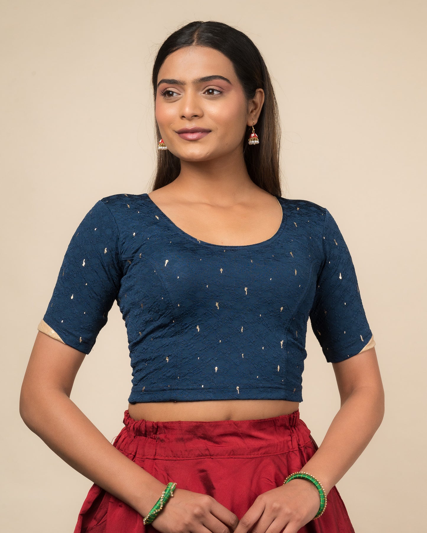 Model wearing a stretchable blouse with round neckline and elbow sleeves featuring metallic drop motifs.