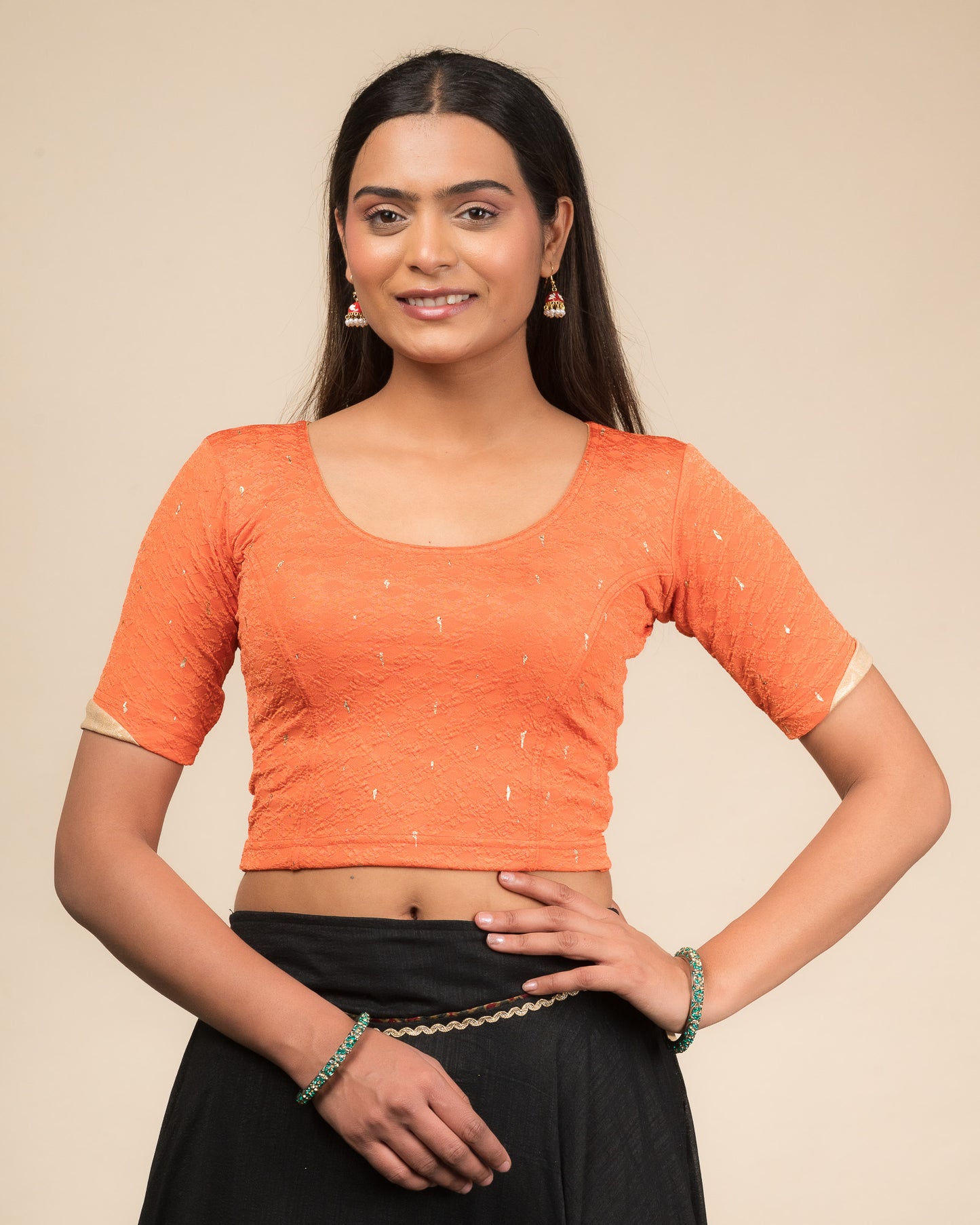 Model wearing a stretchable blouse with round neckline and elbow sleeves featuring metallic drop motifs.
