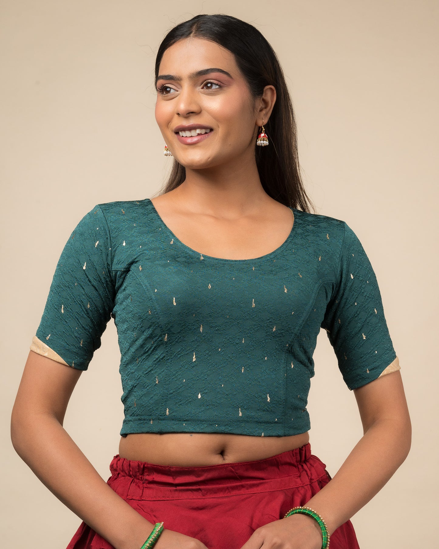 Model wearing a stretchable blouse with round neckline and elbow sleeves featuring metallic drop motifs.