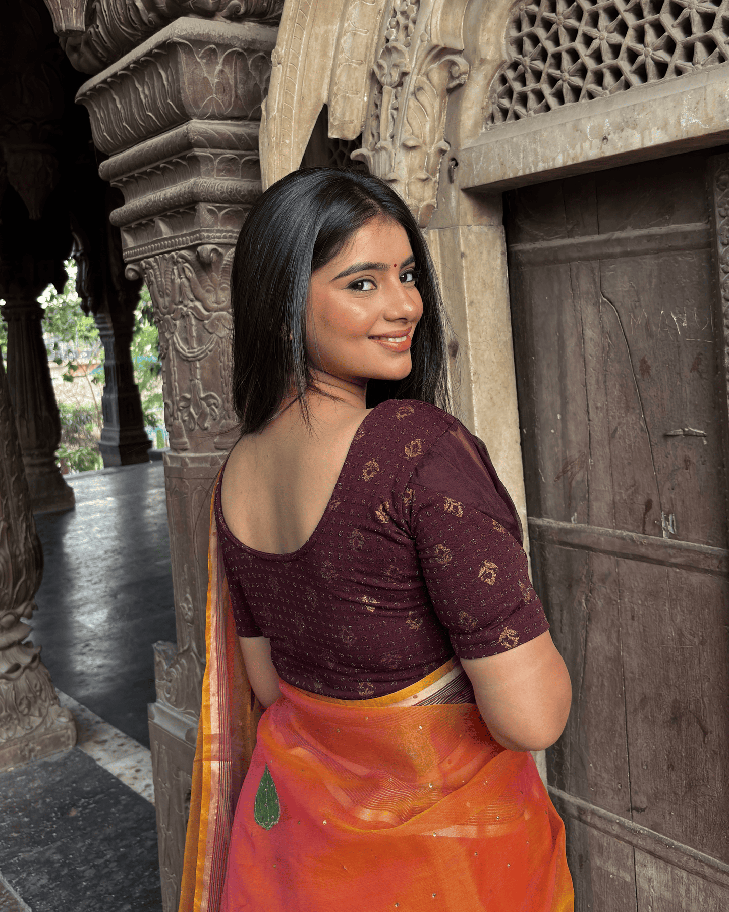 Rear view of the wine jacquard blouse showcasing metallic gold buti detailing and puff sleeve design.