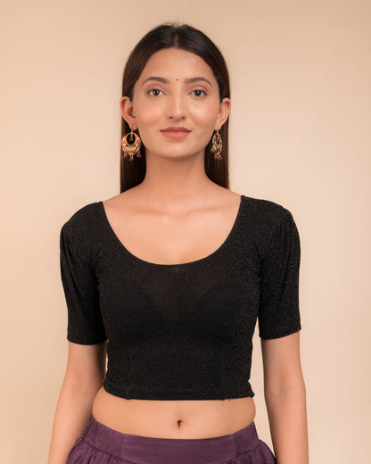 Model wearing a lustrous metallic stretchable blouse with pleated front and round neckline.