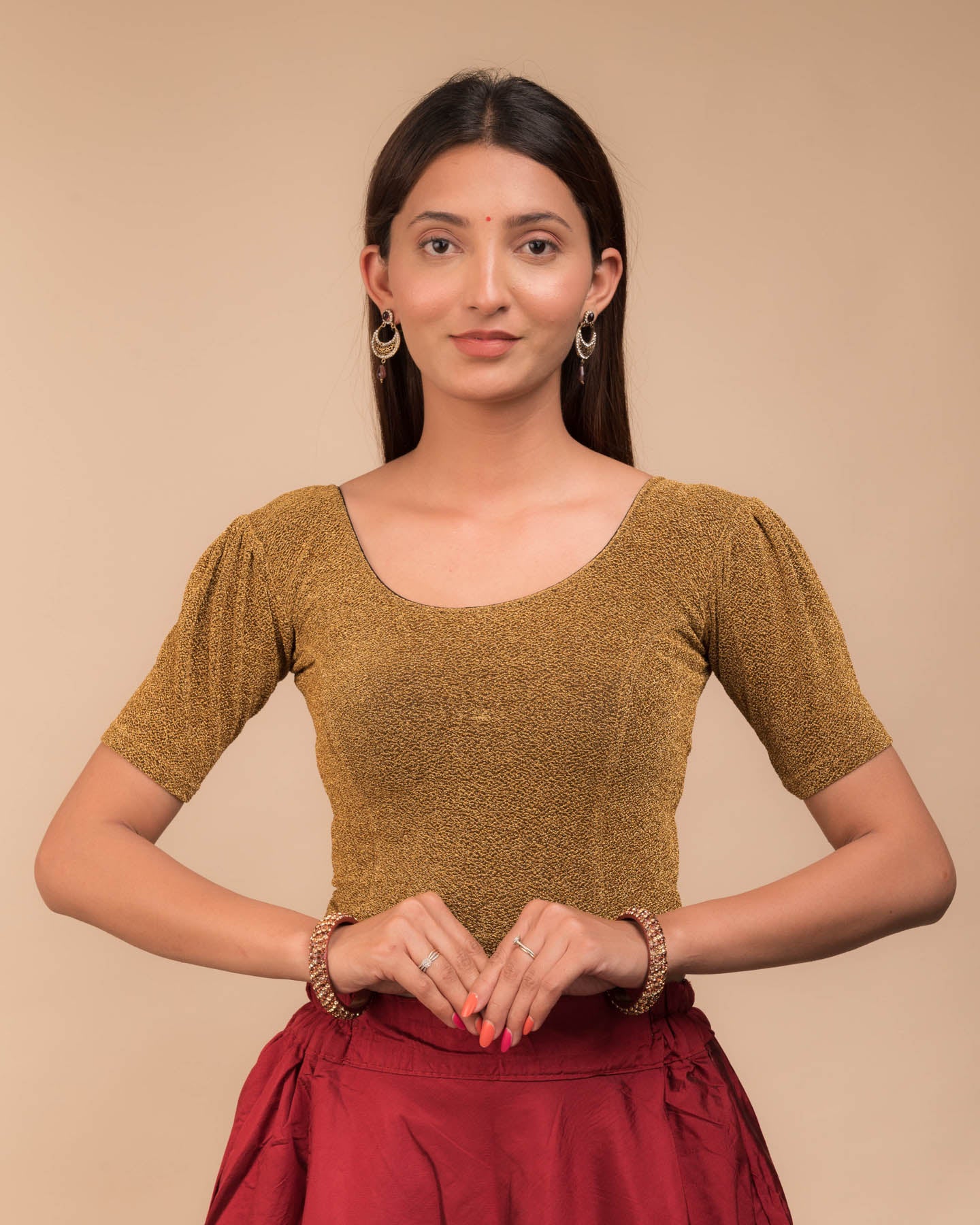 Model wearing a lustrous metallic stretchable blouse with pleated front and round neckline.