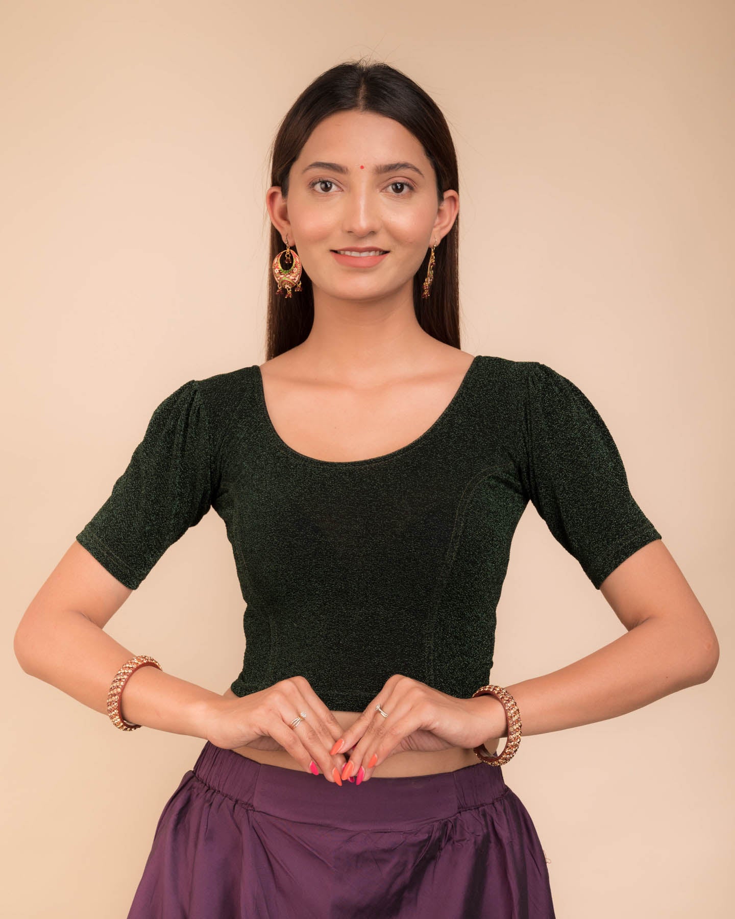Model wearing a lustrous metallic stretchable blouse with pleated front and round neckline.