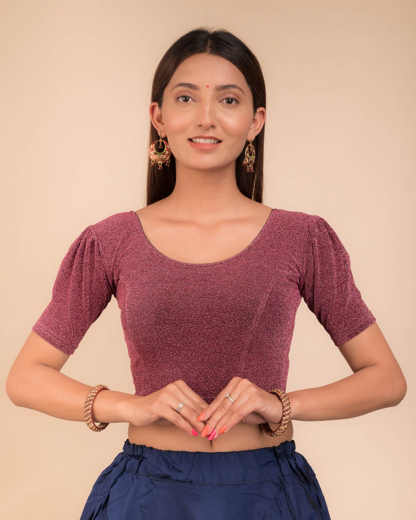 Model wearing a lustrous metallic stretchable blouse with pleated front and round neckline.