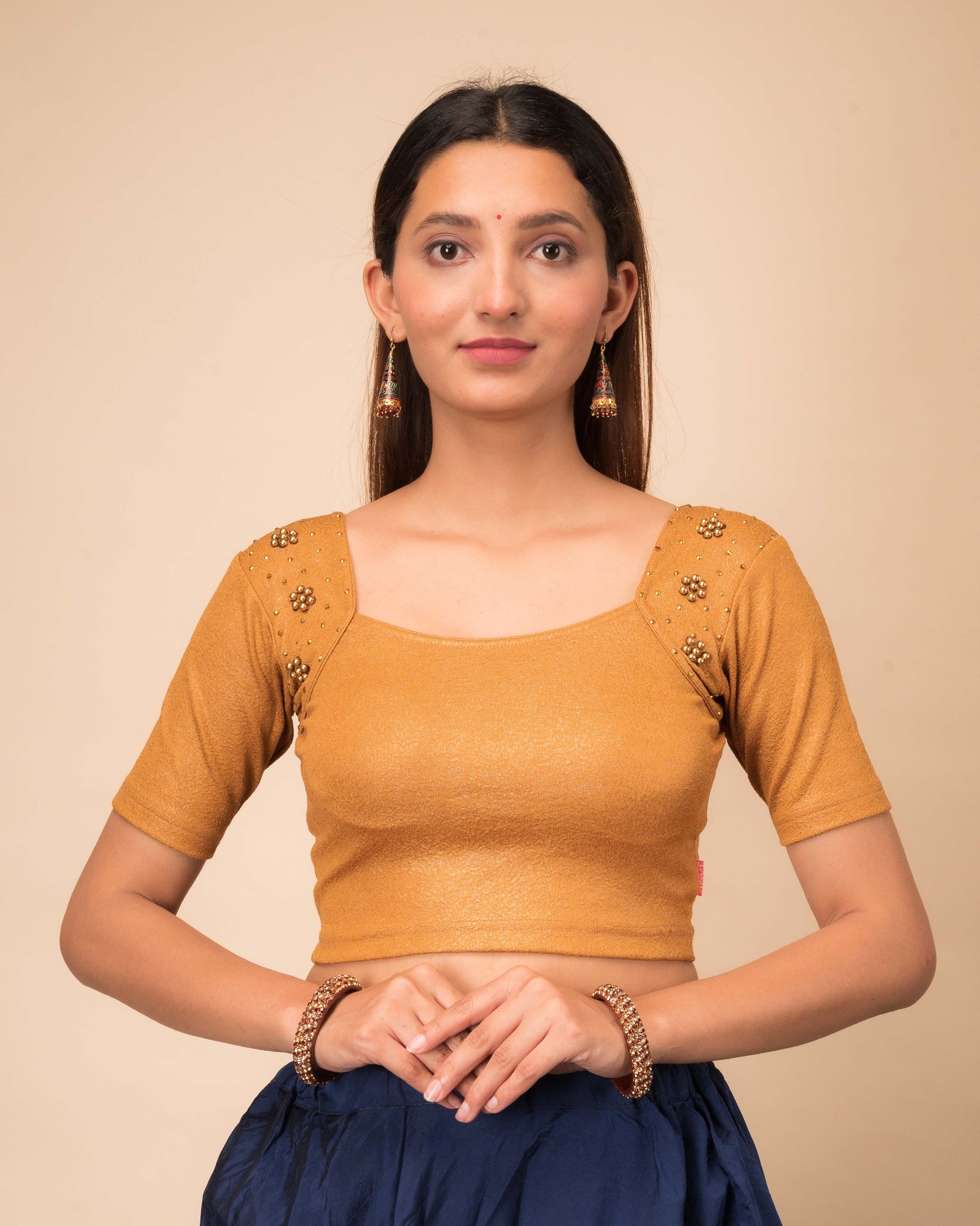 Model wearing a stretchable blouse with a sweetheart neckline and elbow sleeves, adorned with pearl and sequin details.